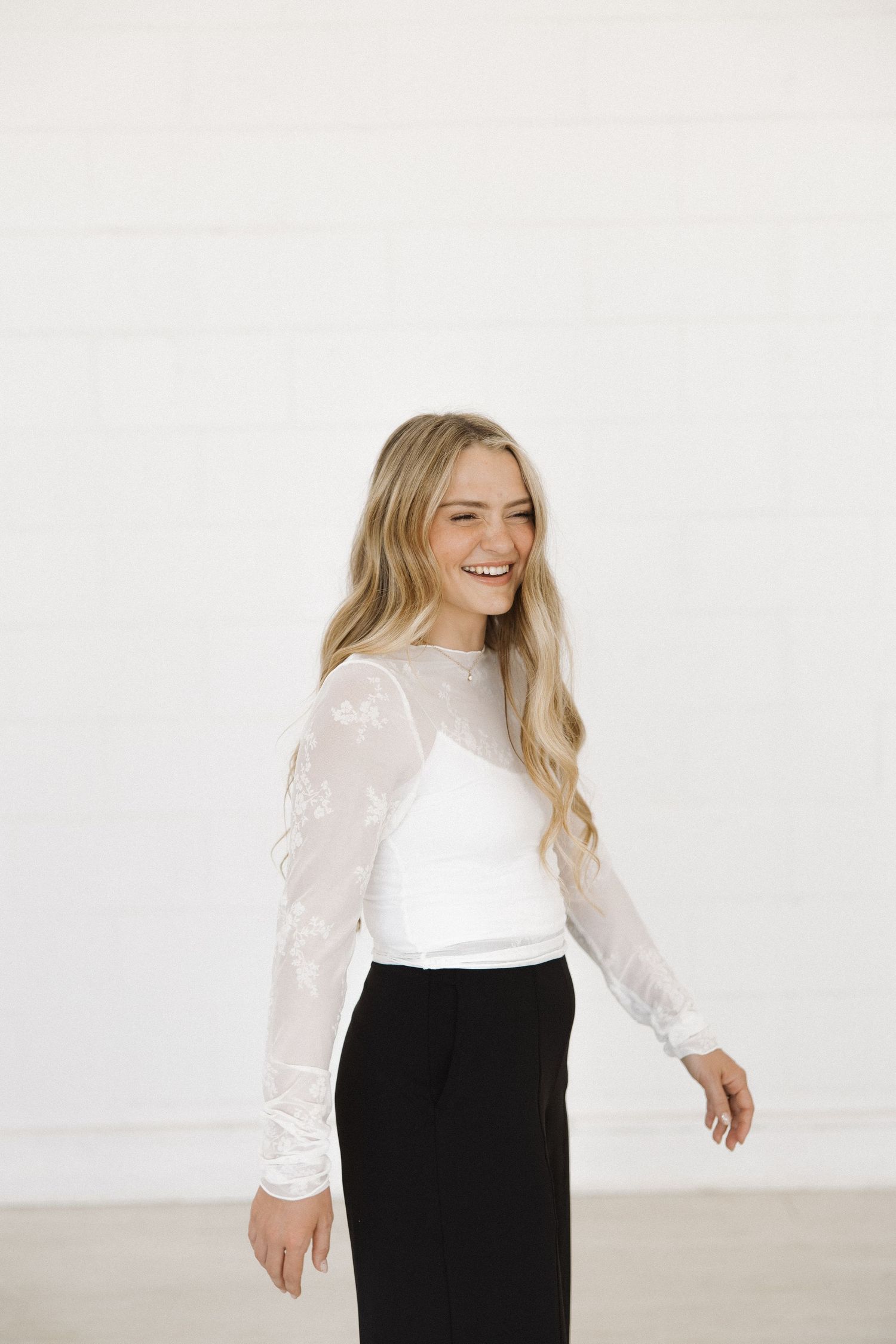 Woman in contrasting outfit smiles joyfully during studio photoshoot.