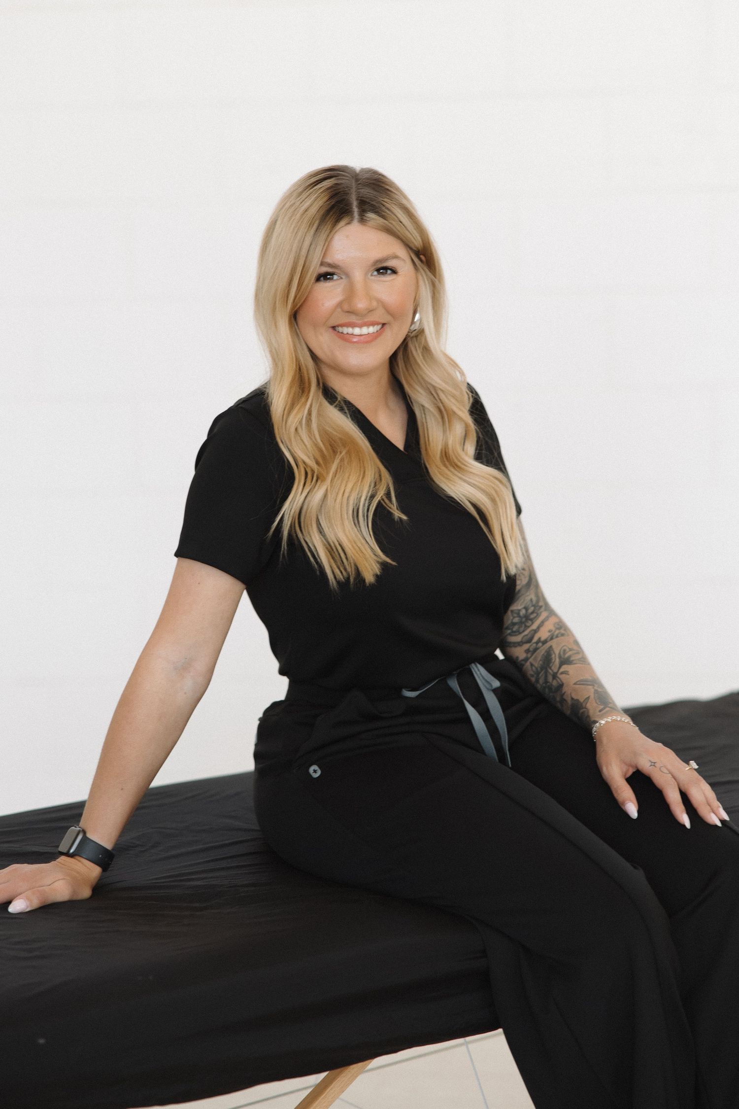 Person in black outfit relaxing on massage table during professional photoshoot.