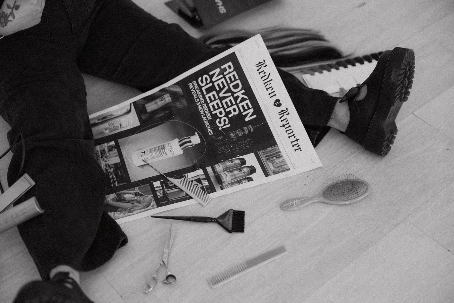 Overhead view of magazines and hair styling tools scattered on light floor.