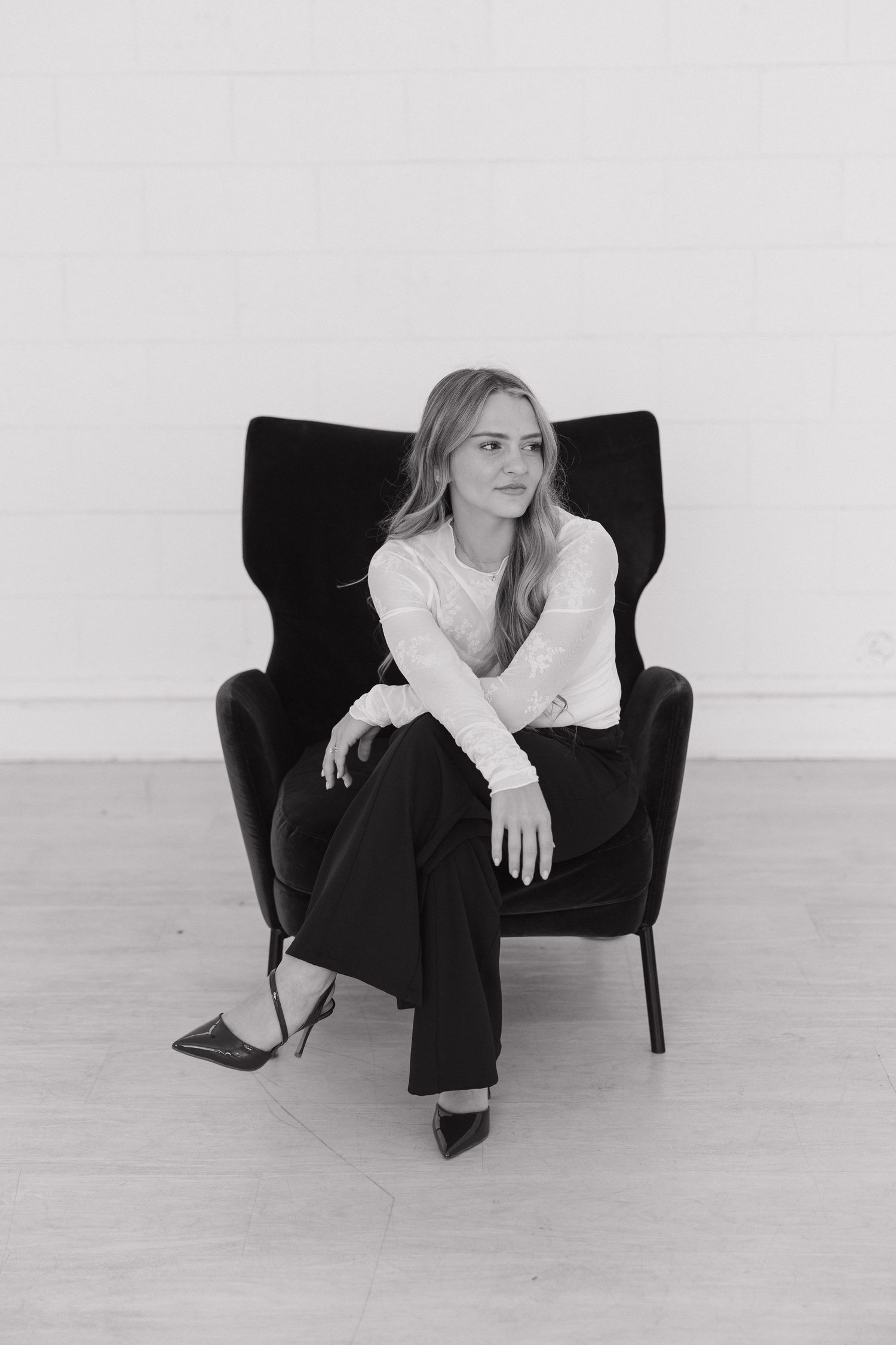 Black and white portrait series showing relaxed poses on dark armchair against minimal white background.