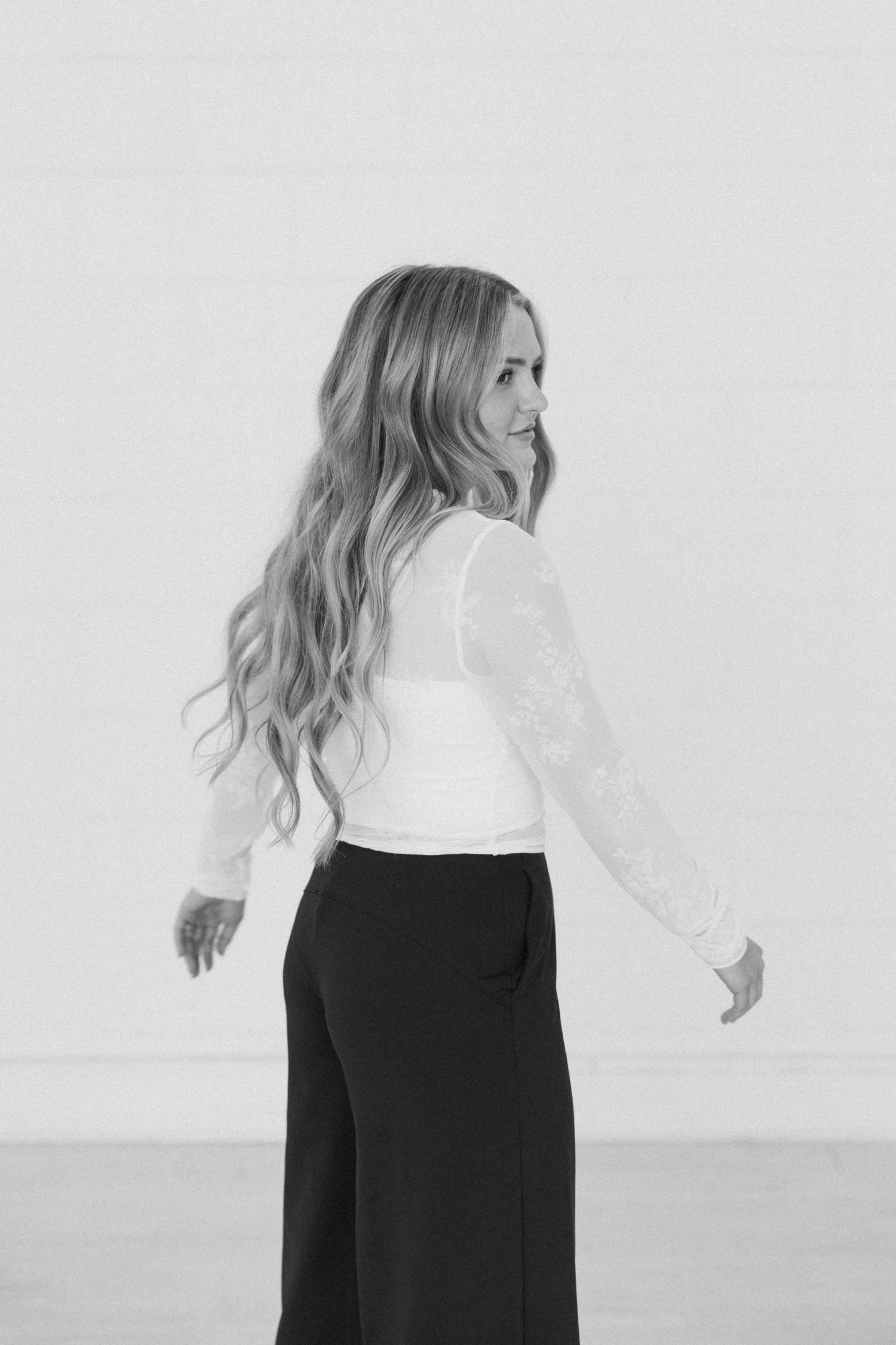 Side view of woman in black and white outfit against minimalist background.
