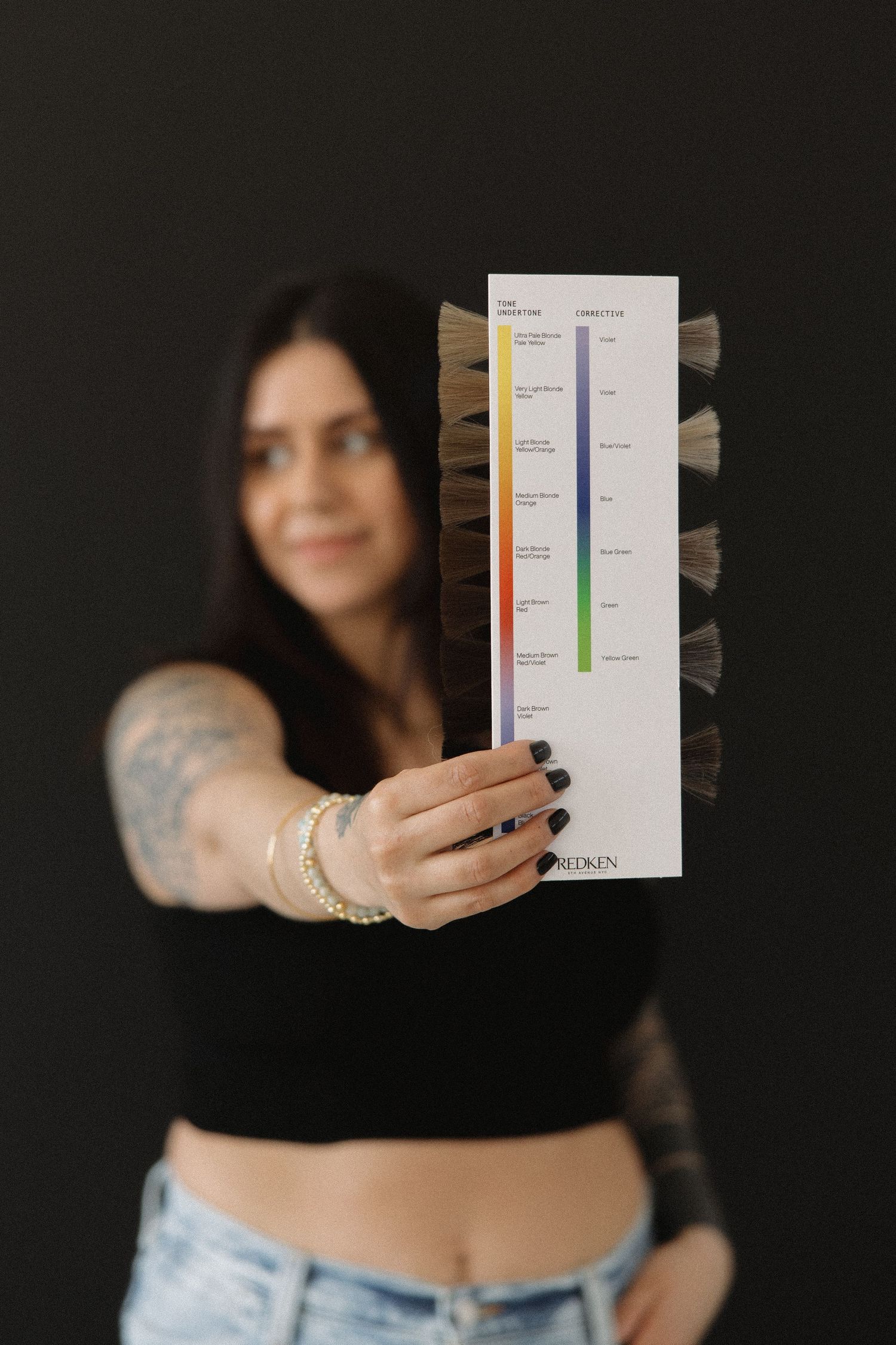 Close up of tattooed arm holding professional hair color swatch palette.