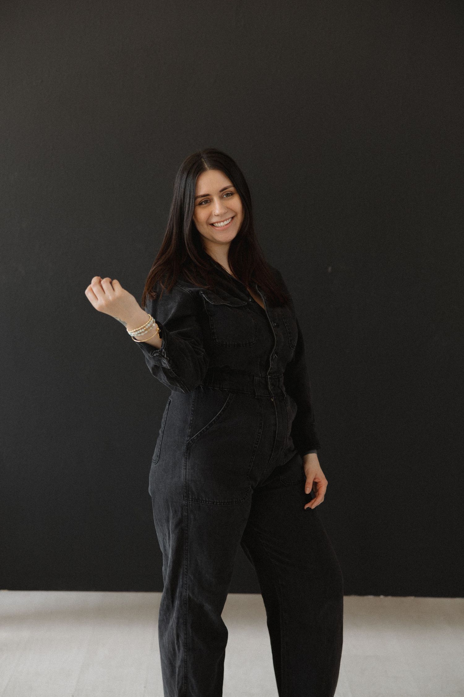 Figure strikes dynamic poses wearing black outfit against dark wall.