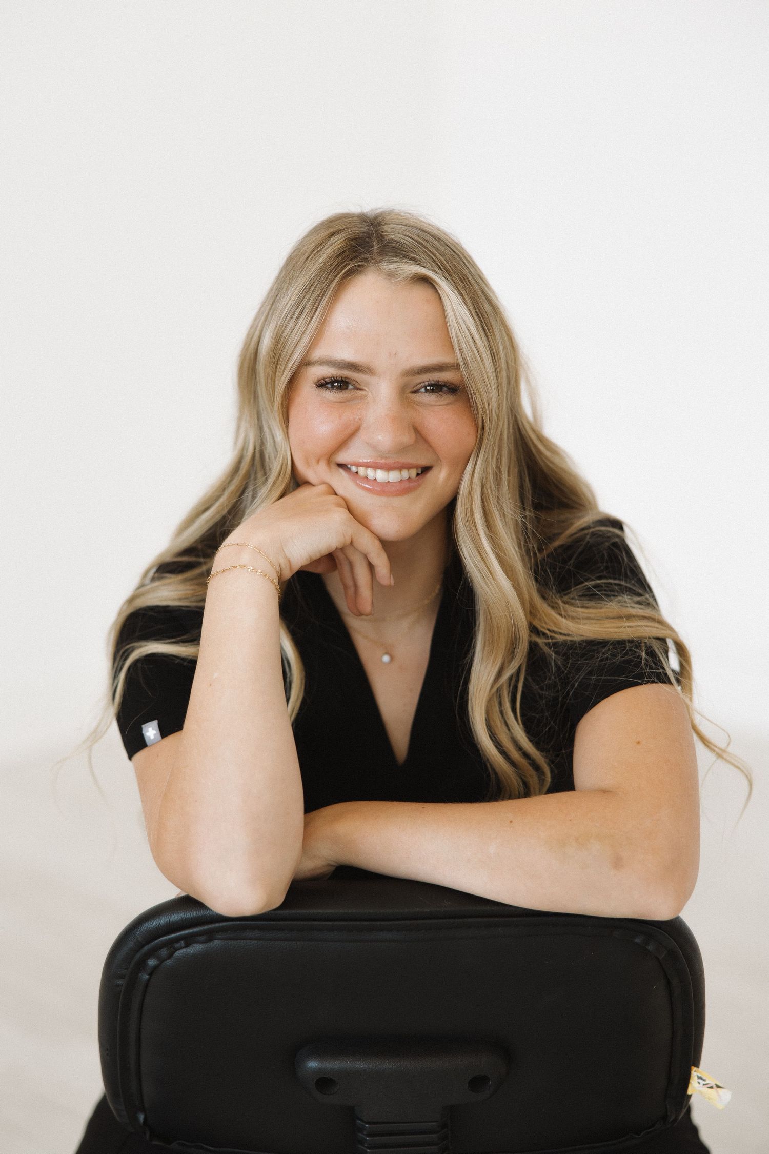 Person leaning on black office chair in casual business attire.