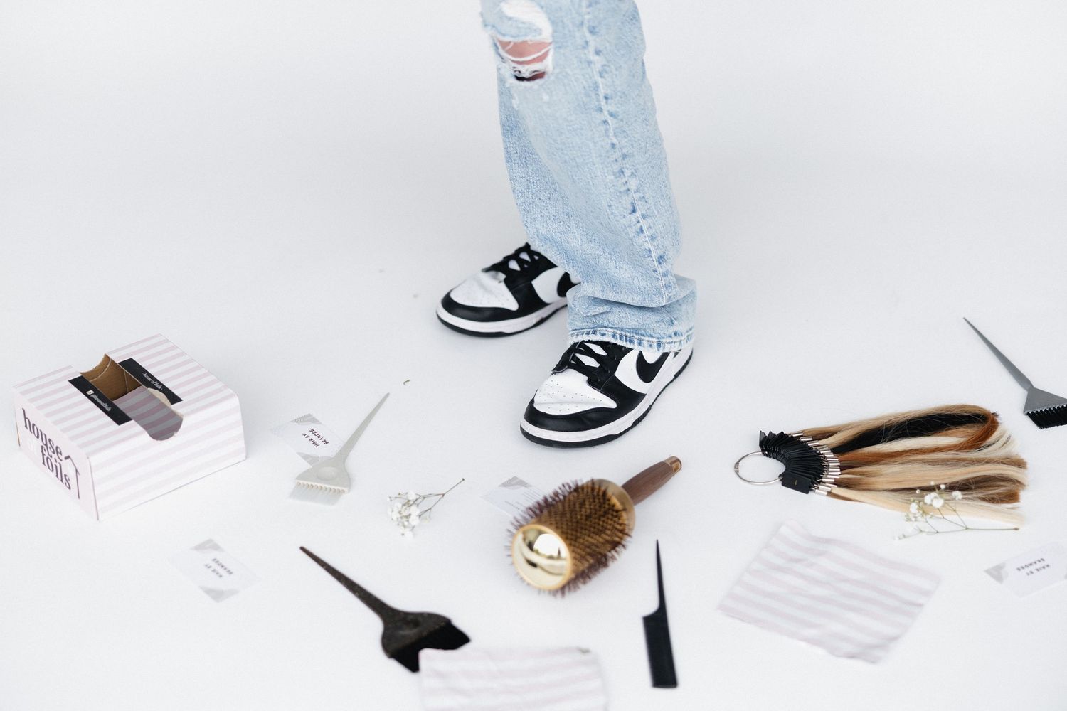Sneakers and beauty styling tools arranged in minimalist composition on white background.