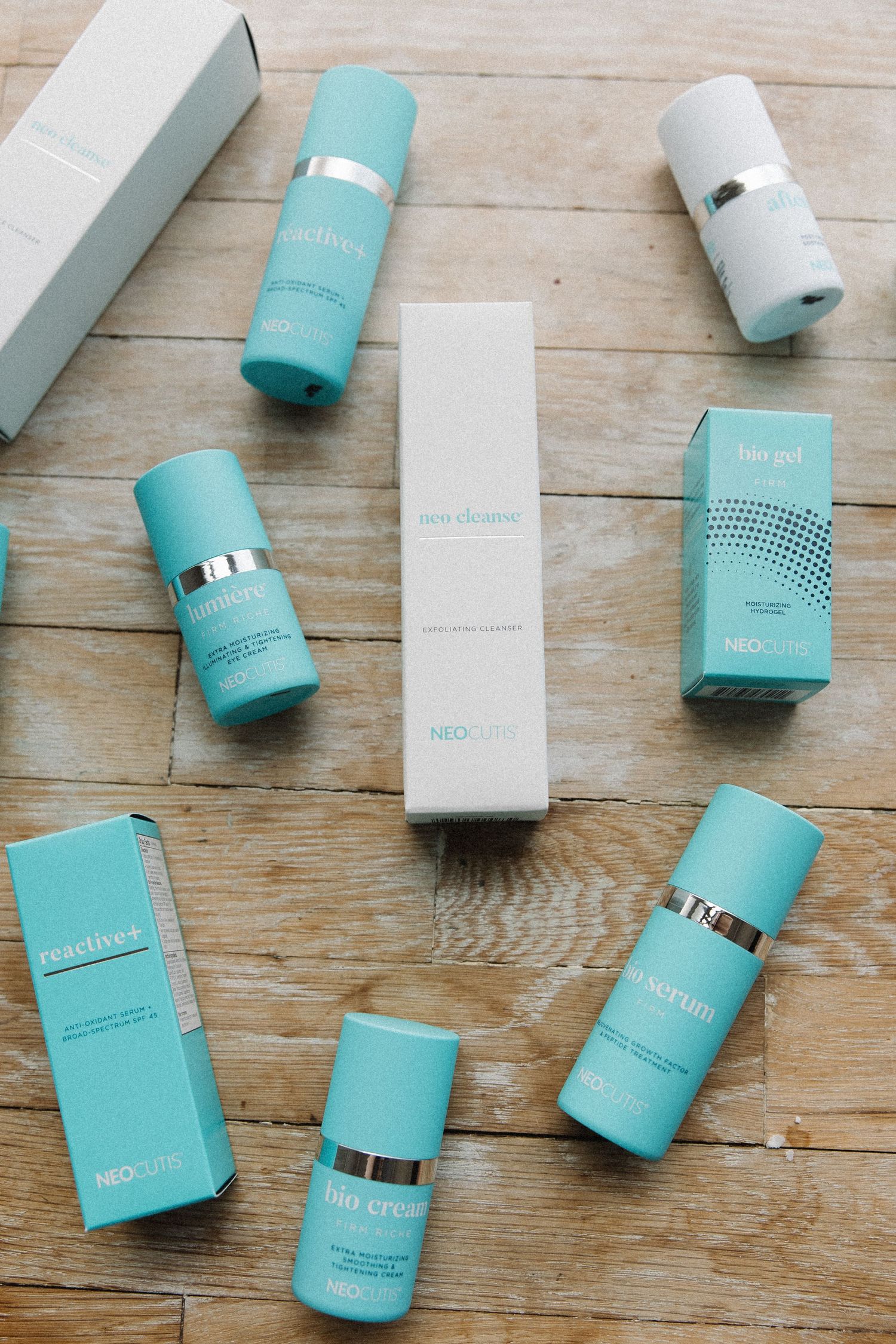 Turquoise and white skincare products scattered artistically on wooden background.