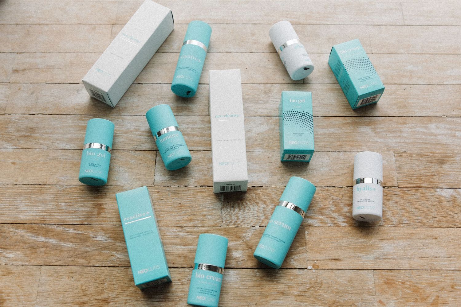 Scattered turquoise and white cosmetic products on wooden floor.