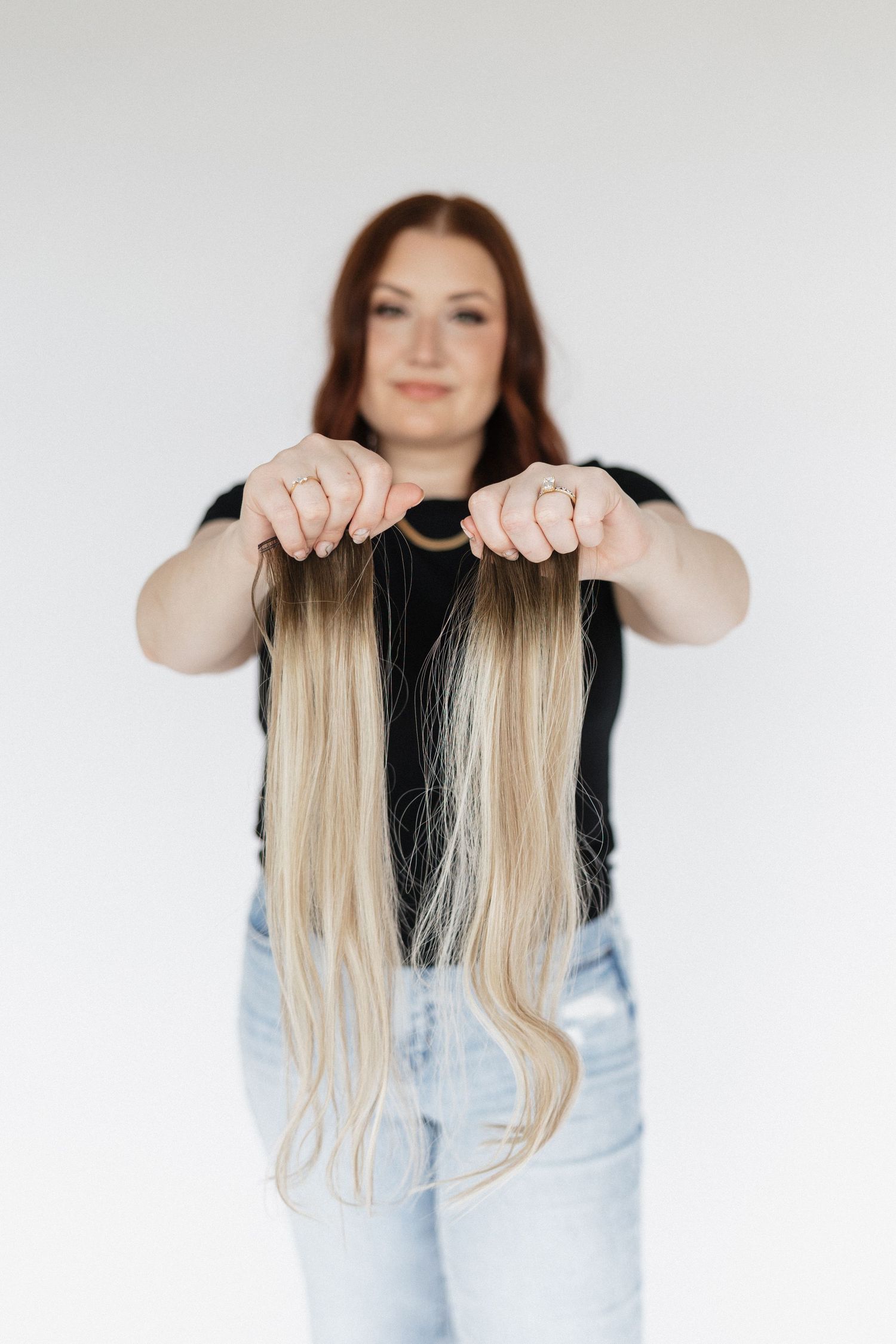 Demonstrating blonde hair extensions in a bright studio setting.