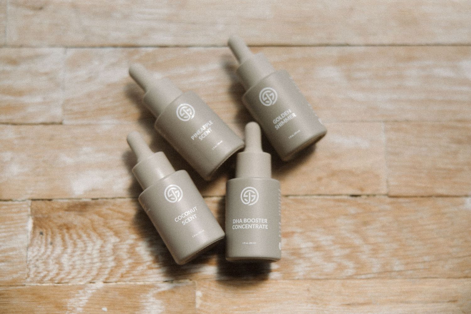 Four SJOLIE product bottles lying on wooden surface showing brand packaging.