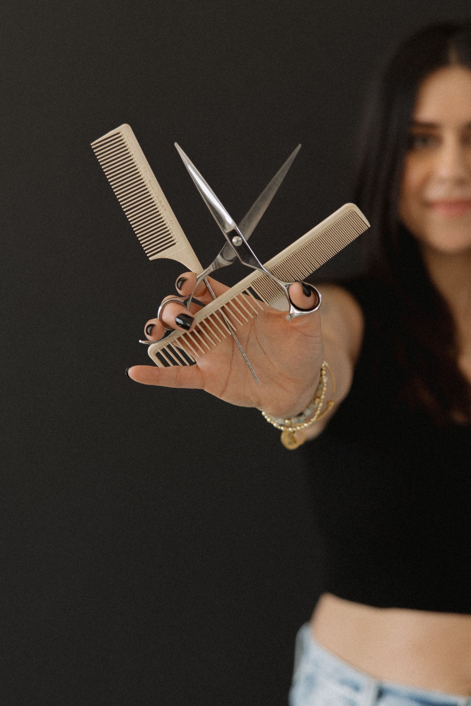 Hair styling tools arranged to create a playful dinosaur shape against a dark background.