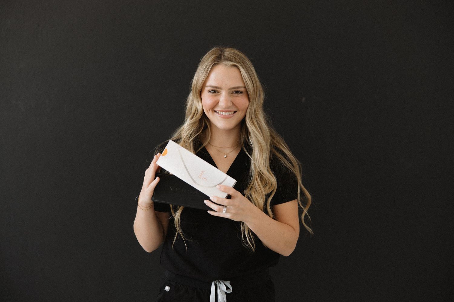 Medical professional holds white product package against dark background.