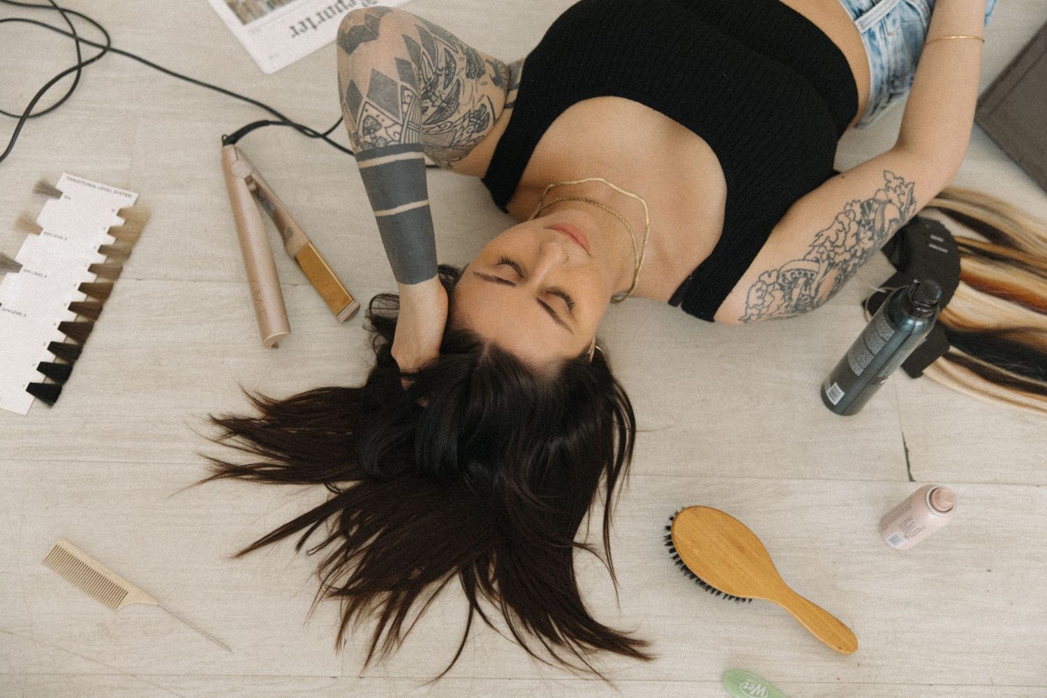 Lifestyle photo with person lying down surrounded by hair styling tools and beauty supplies.