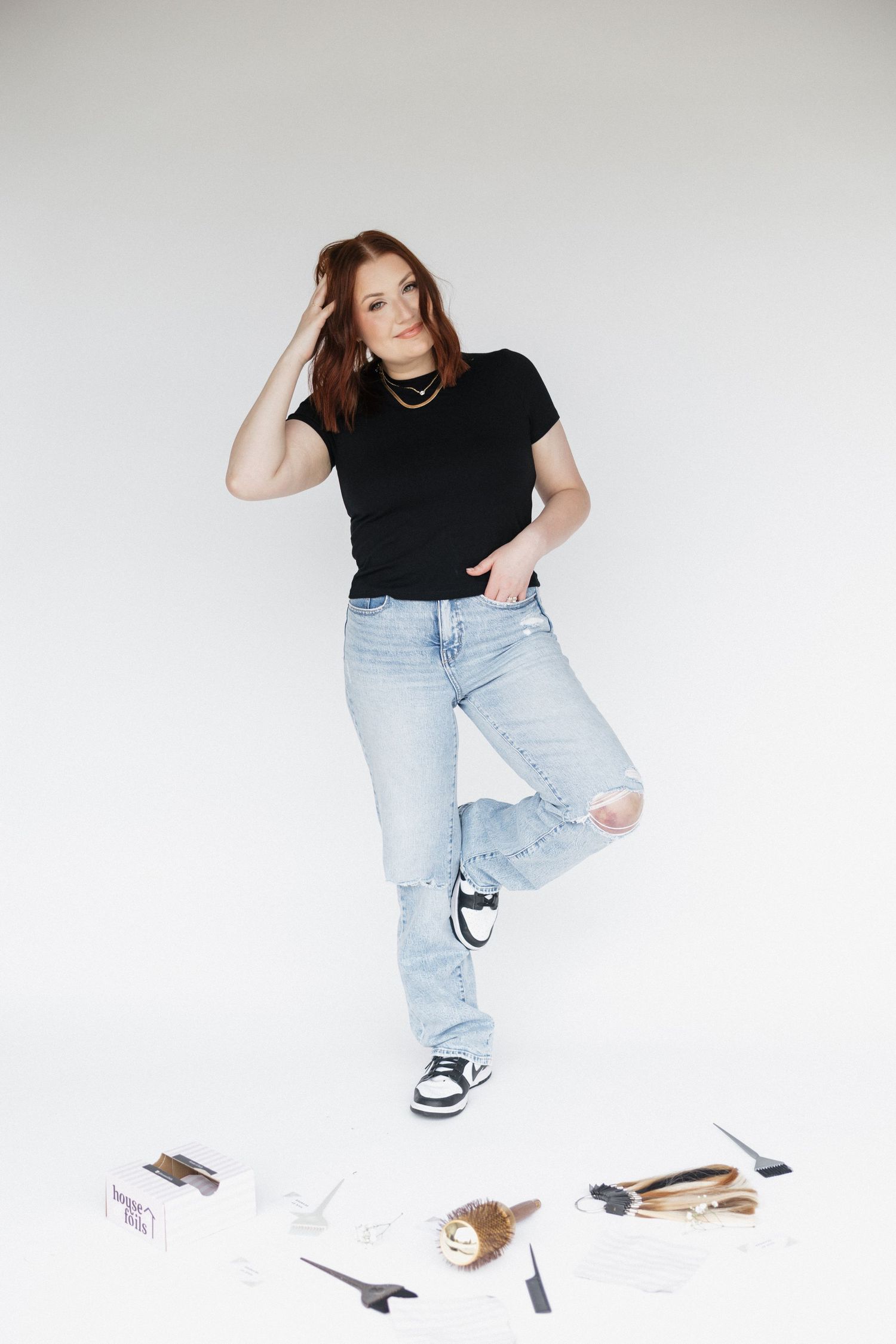 Creative studio poses with light denim jeans and black top on white background.