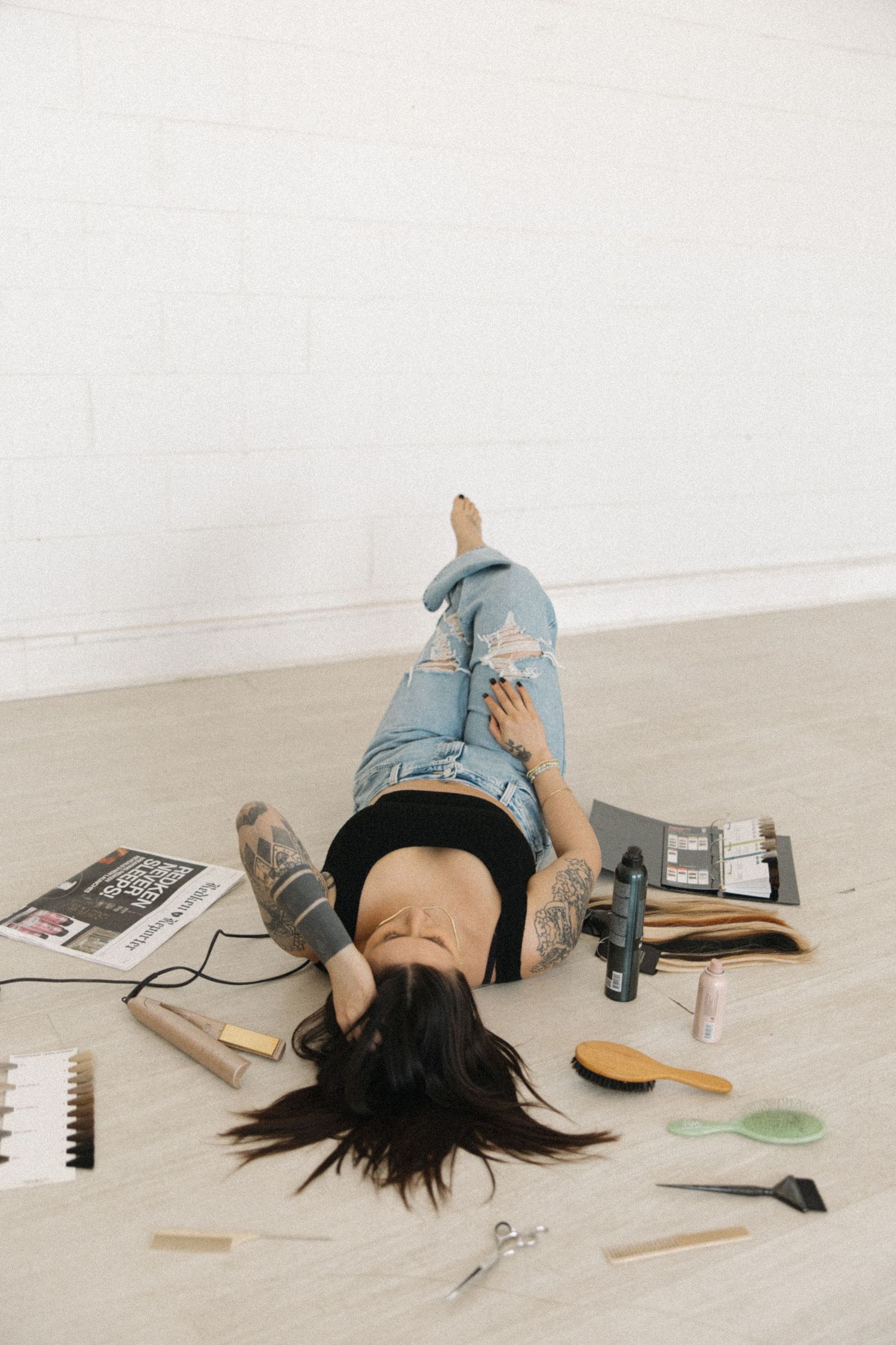 Casual lifestyle image showing someone relaxing on floor with scattered hair styling items.