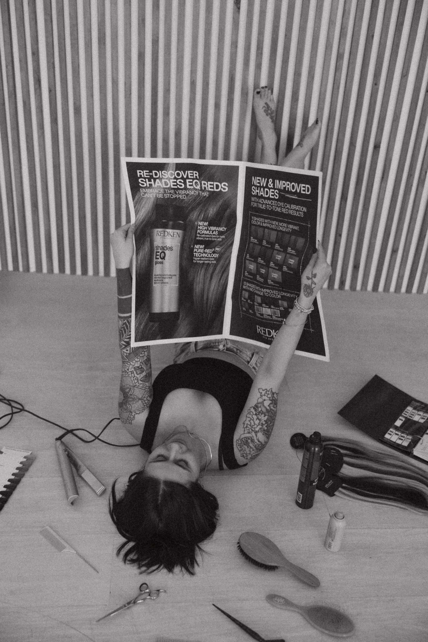 Black and white photo with beauty products and magazines arranged around reclining figure.