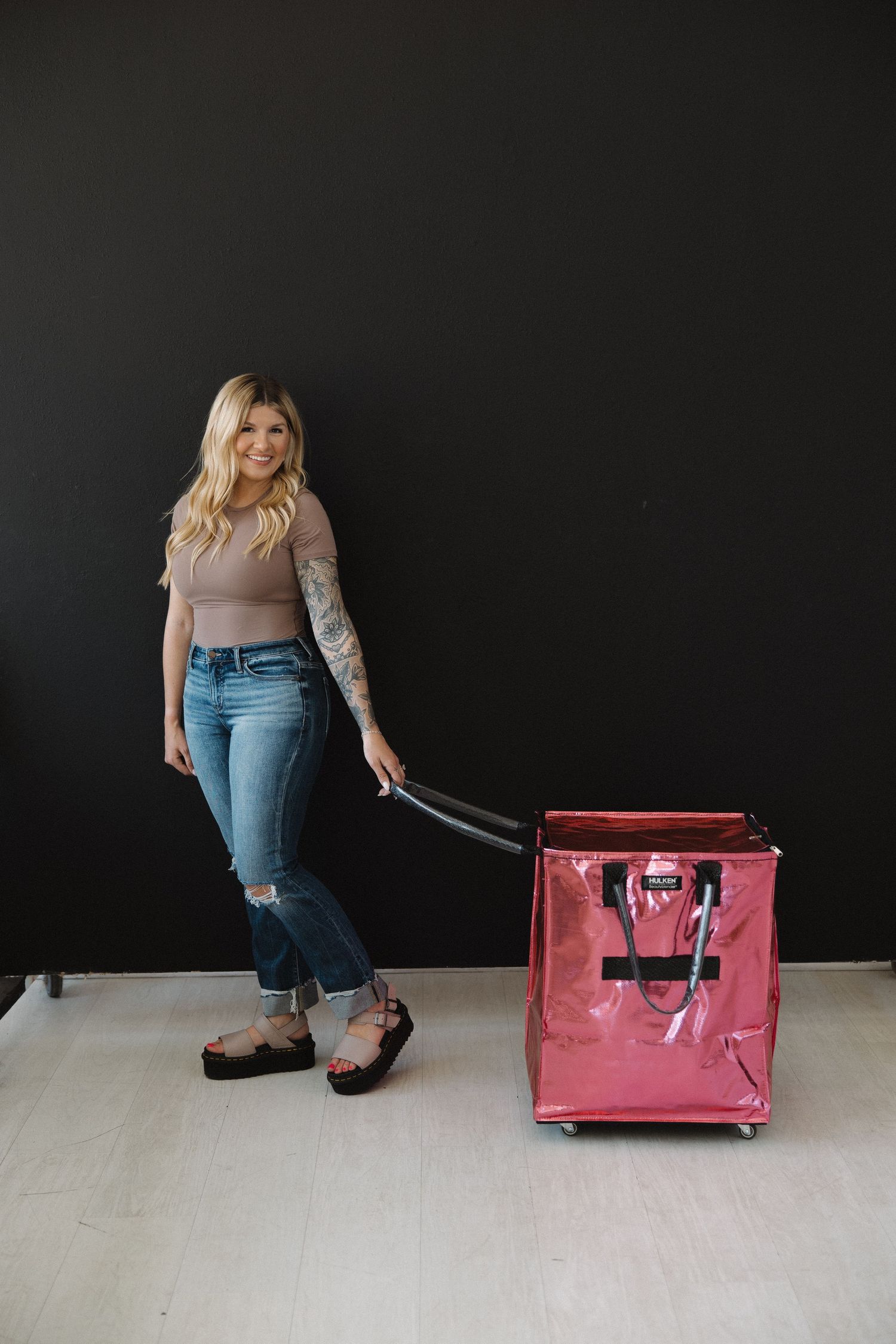 Pink rolling storage cart against black backdrop with beauty equipment.