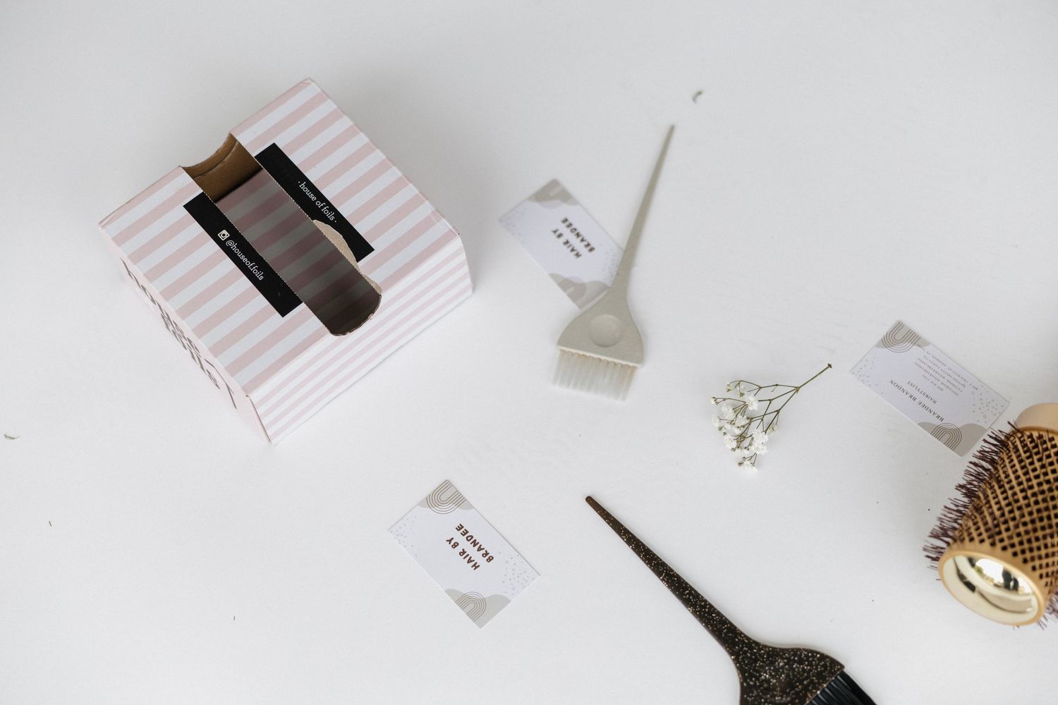 Flat lay of professional hair styling tools and accessories on white background.