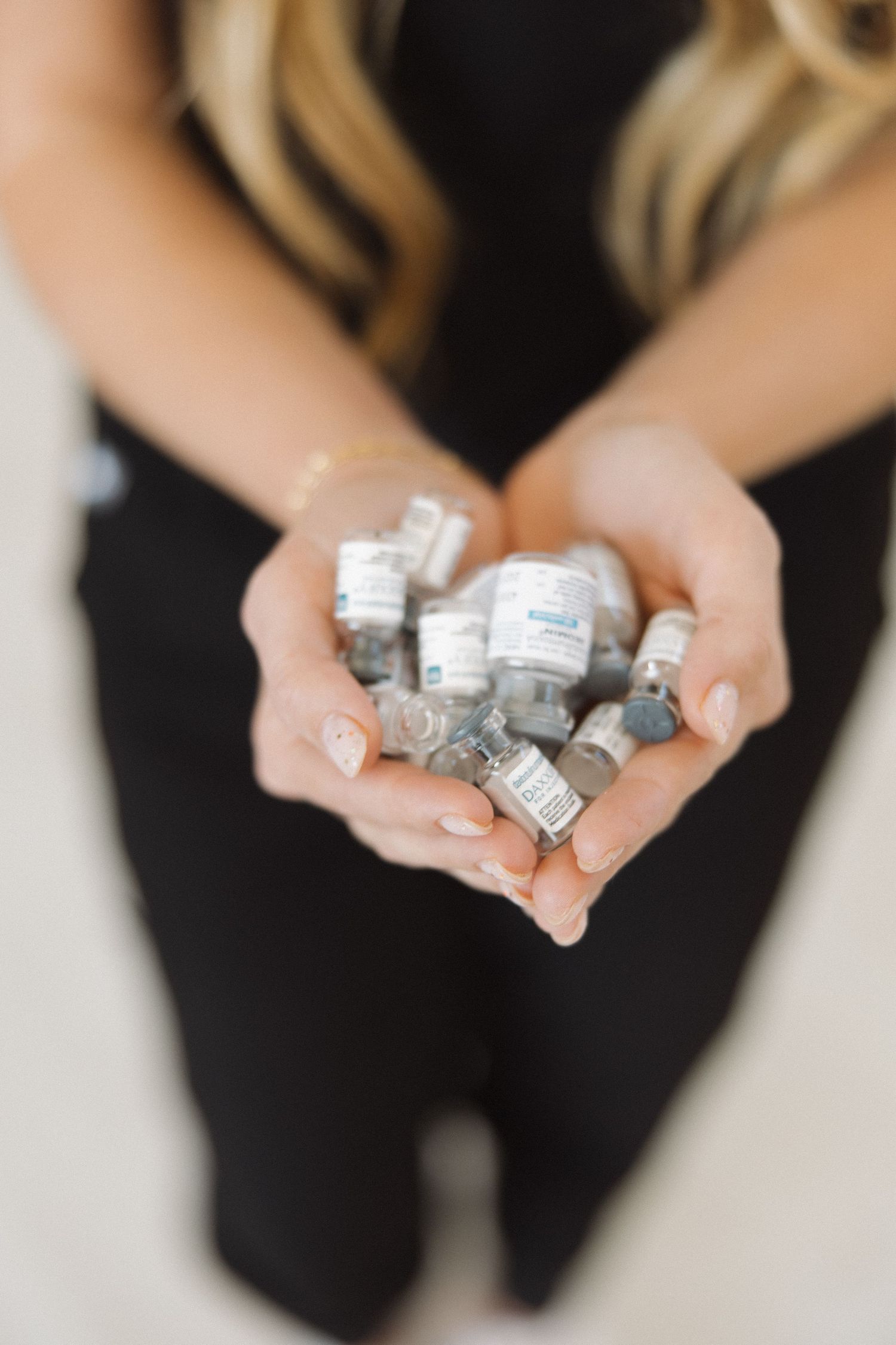Close-up of hands holding multiple medical vials and containers.
