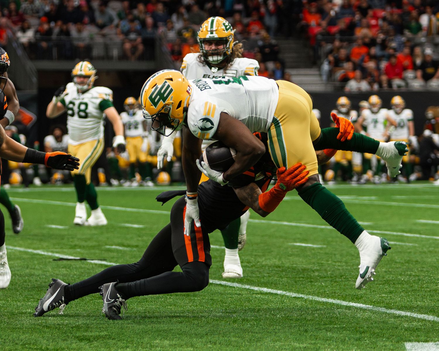 Green Bay Packers player carries the ball while being tackled by a Cleveland Browns defender during an NFL game.