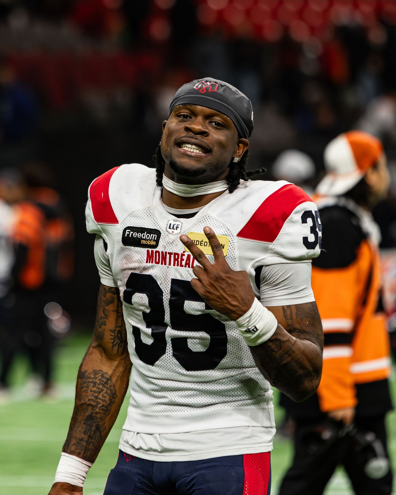 Montreal Alouettes player #35 smiles on field in white uniform after CFL football game.
