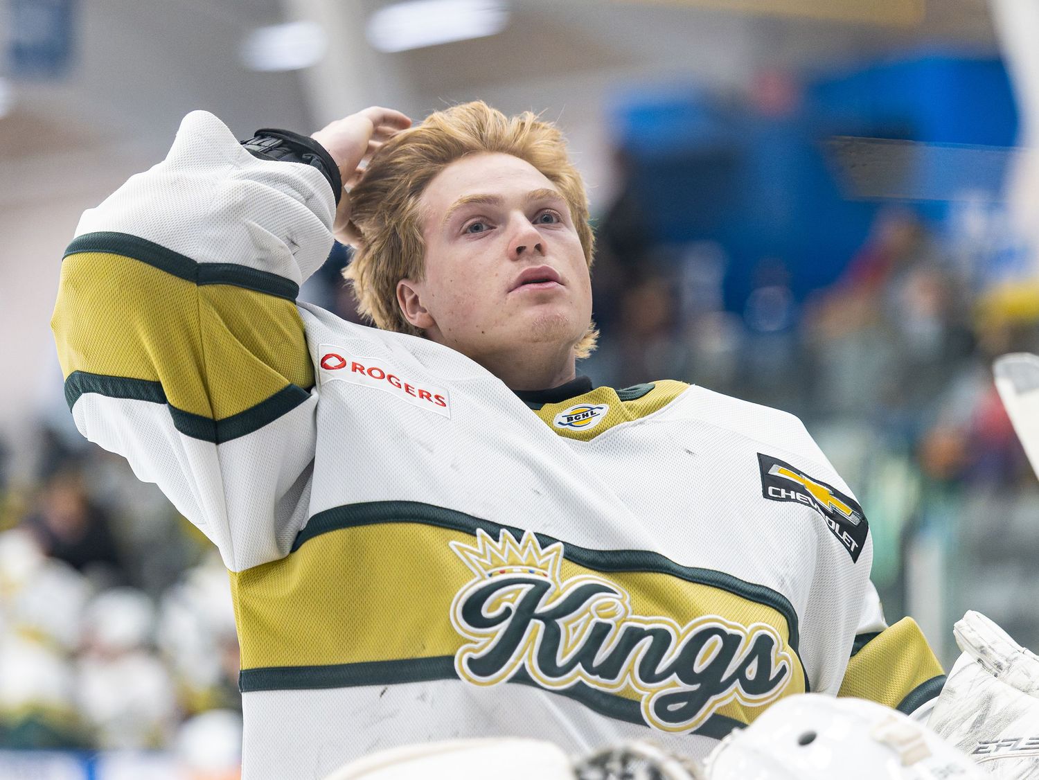 Hockey player in Kings jersey looks up pensively on the bench during a game.