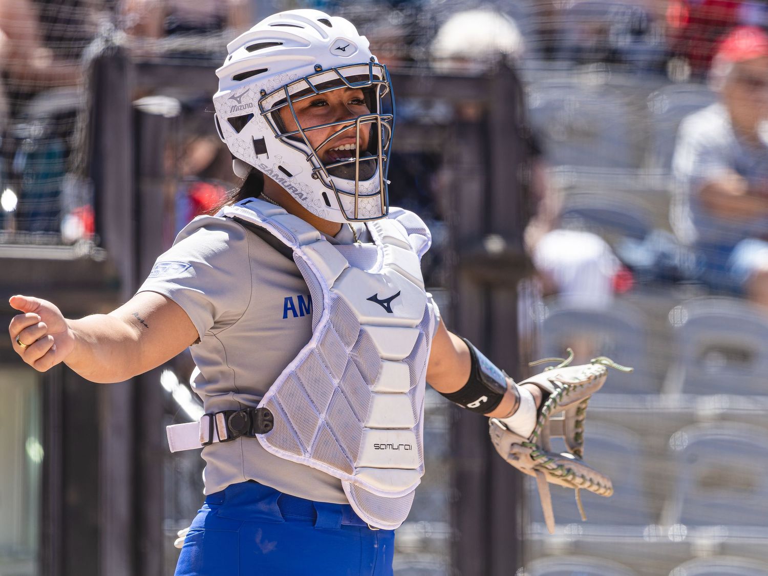 Baseball catcher in white Mizuno gear and helmet ready for play on a sunny day.