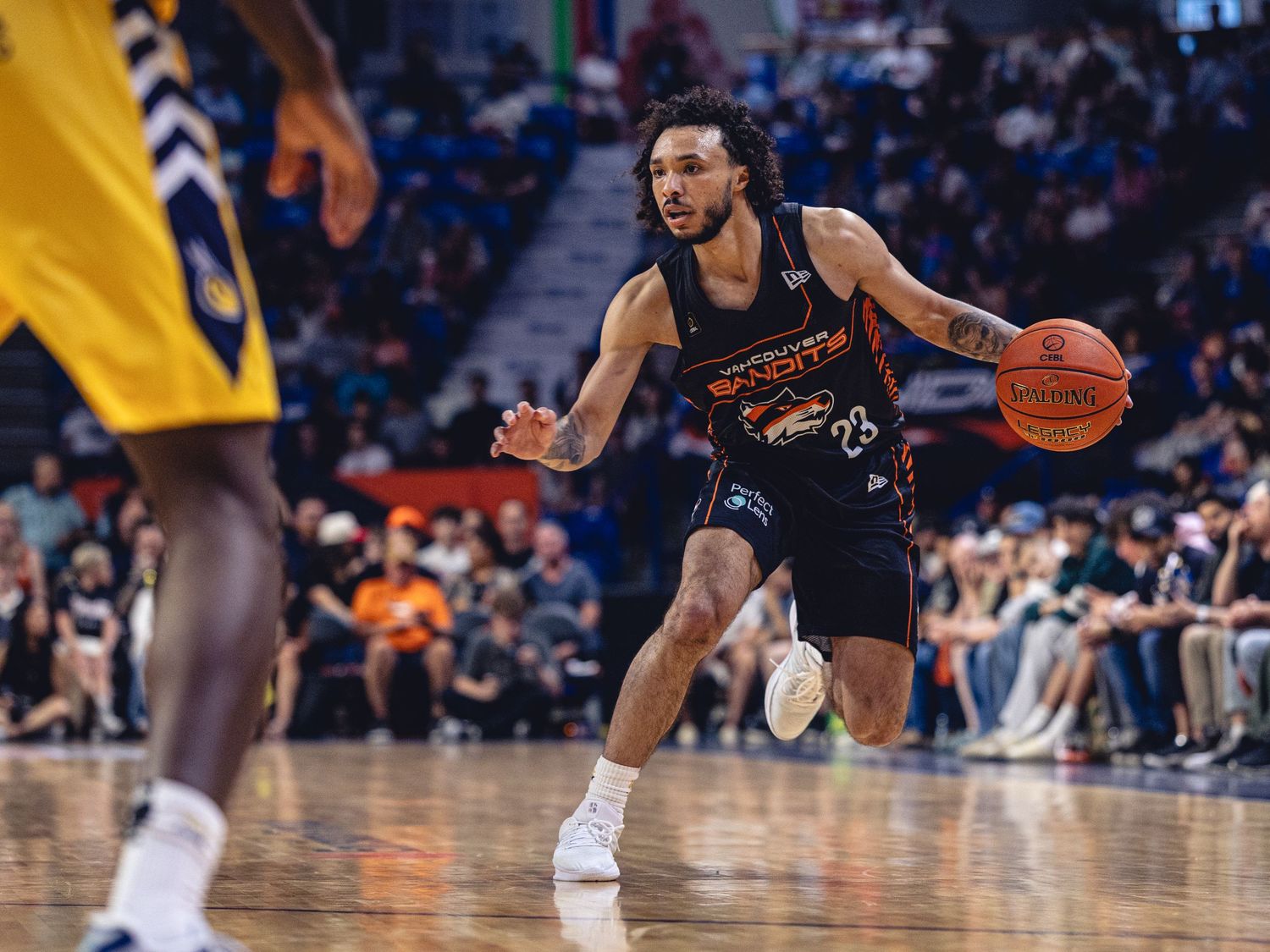 Basketball player in black uniform dribbles ball during professional game on indoor court.
