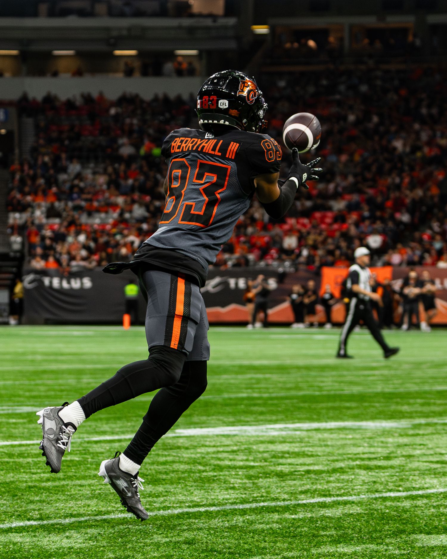 BC Lions player #83 catches a football on the field during a CFL night game at BC Place stadium.