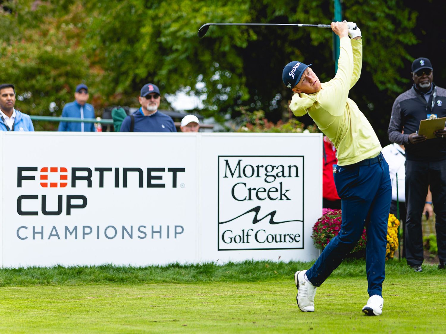 Golfer tees off at Fortinet Cup Championship at Morgan Creek Golf Course with spectators watching.