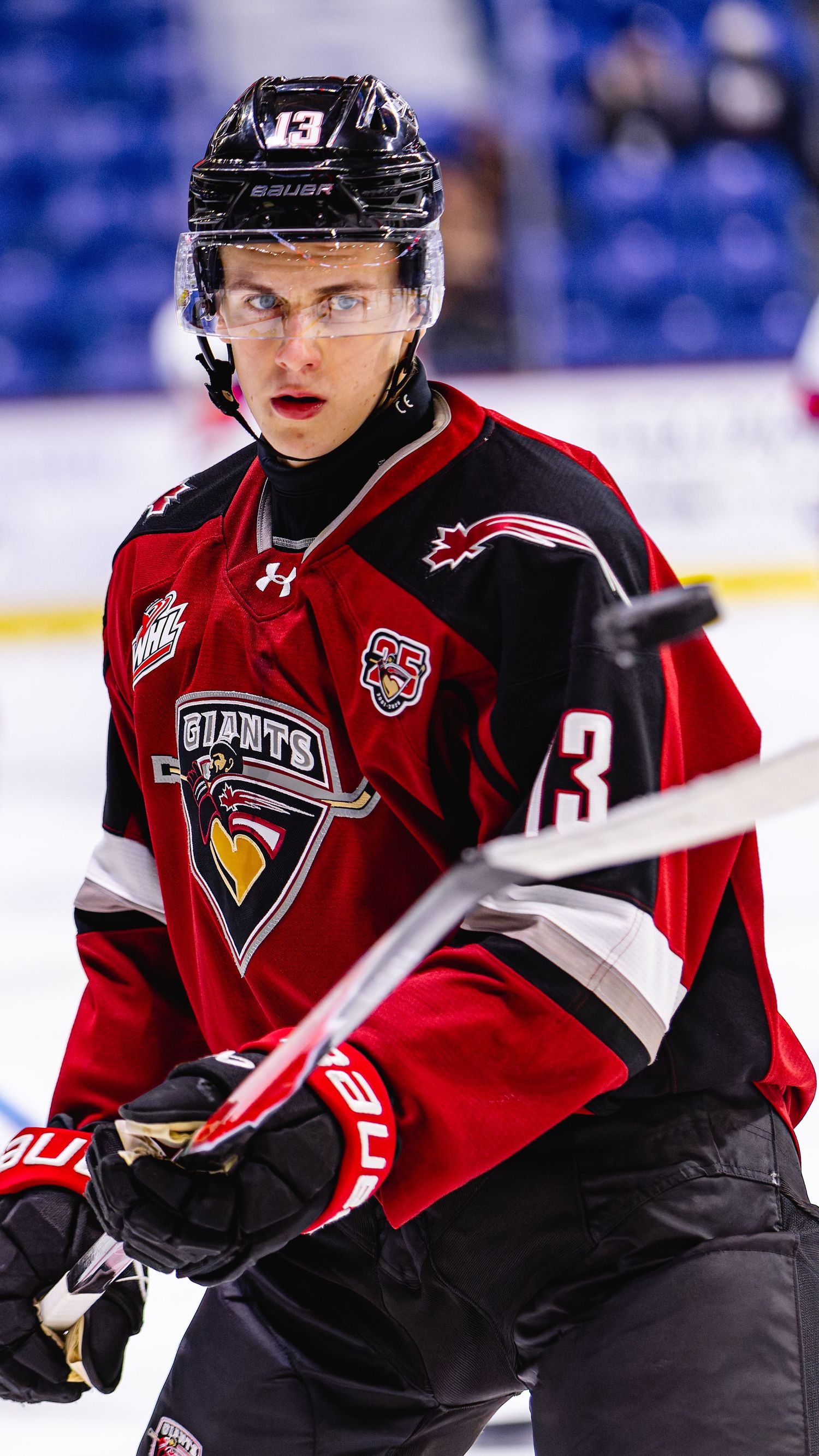 Hockey player wearing a red and black Vancouver Giants WHL jersey number 13 skating on ice during a game.