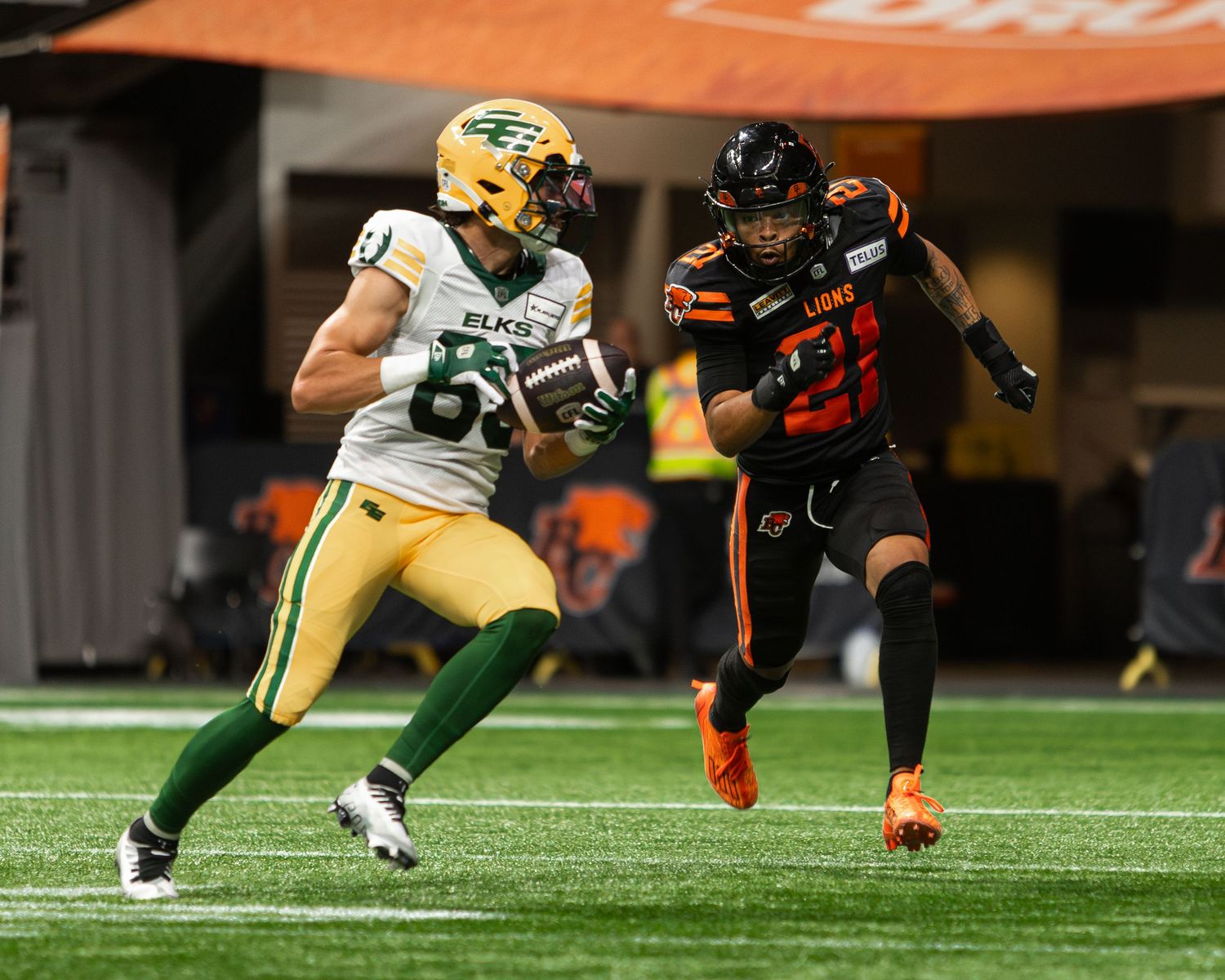 Edmonton Elks receiver runs with the ball while a BC Lions defender pursues during a CFL game.
