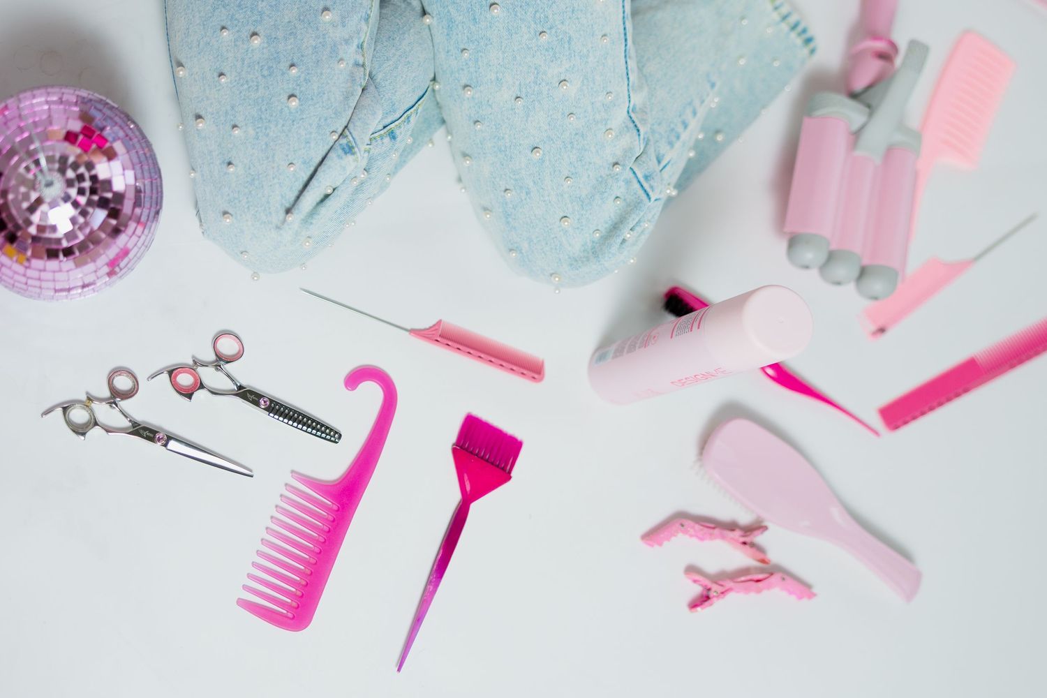 Collection of pink hair styling tools and accessories arranged on white surface.