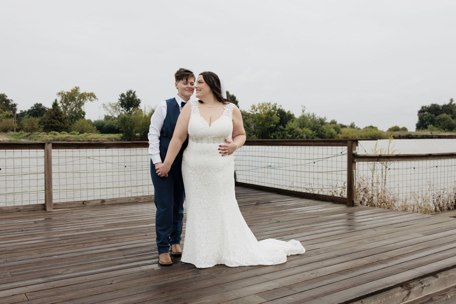 Wedding couple poses on a rustic wooden boardwalk surrounded by natural scenery.