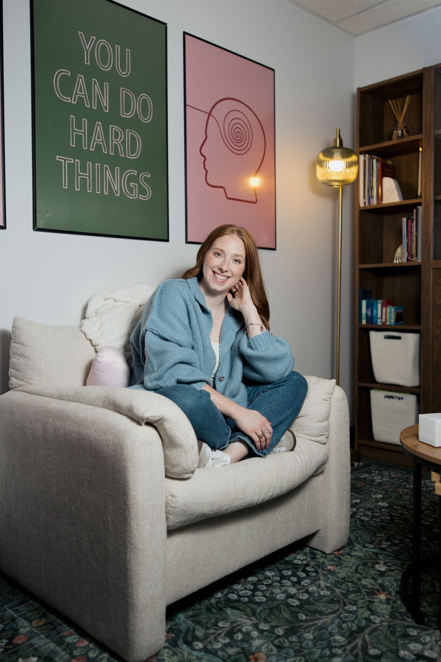Interior room with motivational wall art and grey couch against green and pink walls.