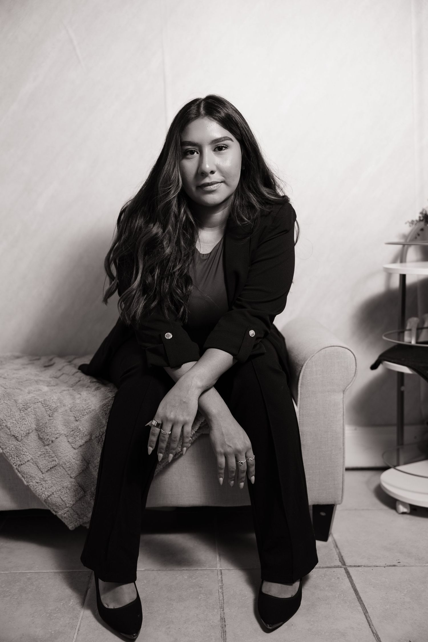Professional black and white portrait of a person in business attire sitting on a couch.