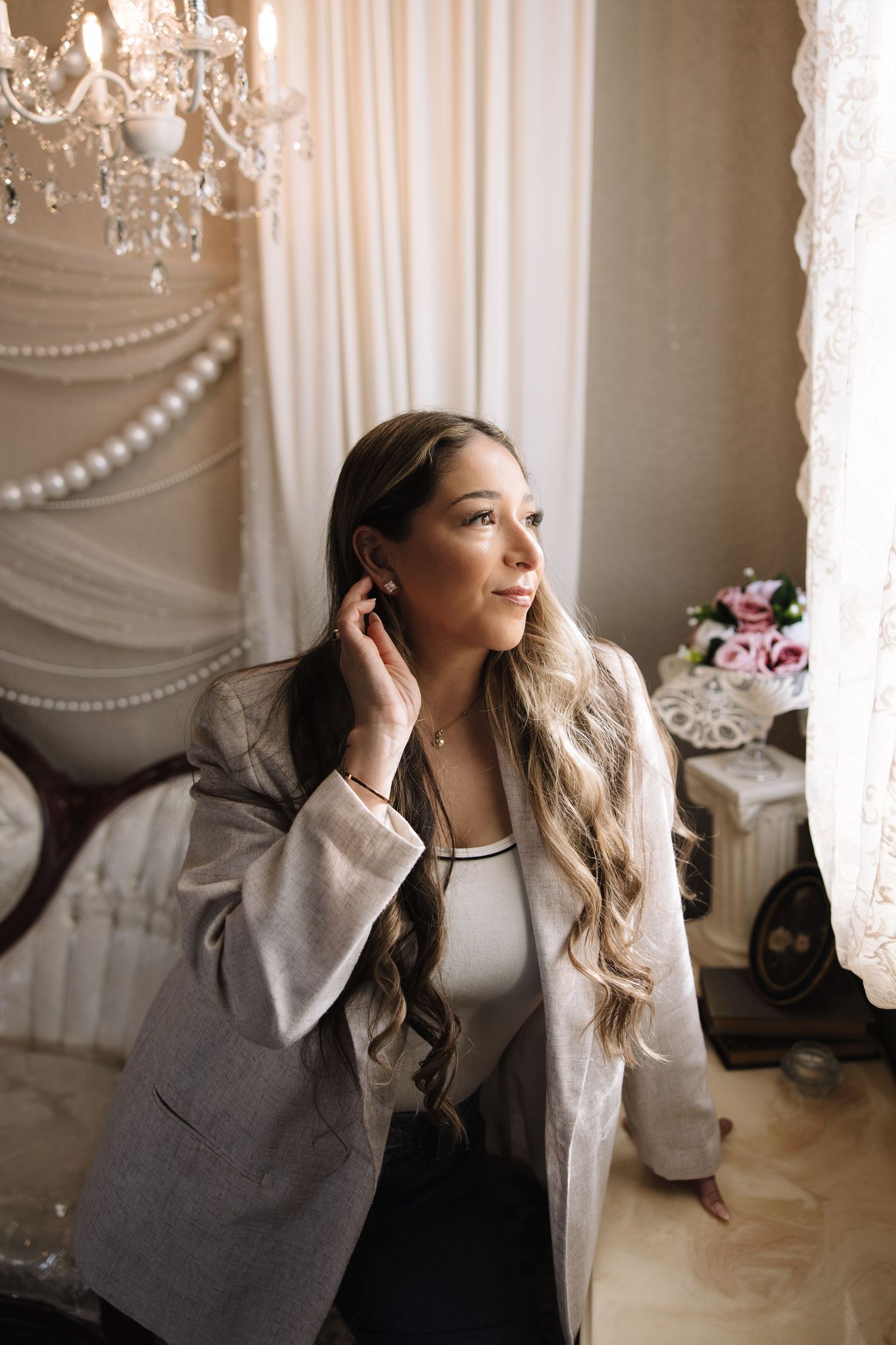 A series of four elegant portraits showing a woman in a gray blazer posing against a light backdrop with crystal chandeliers.