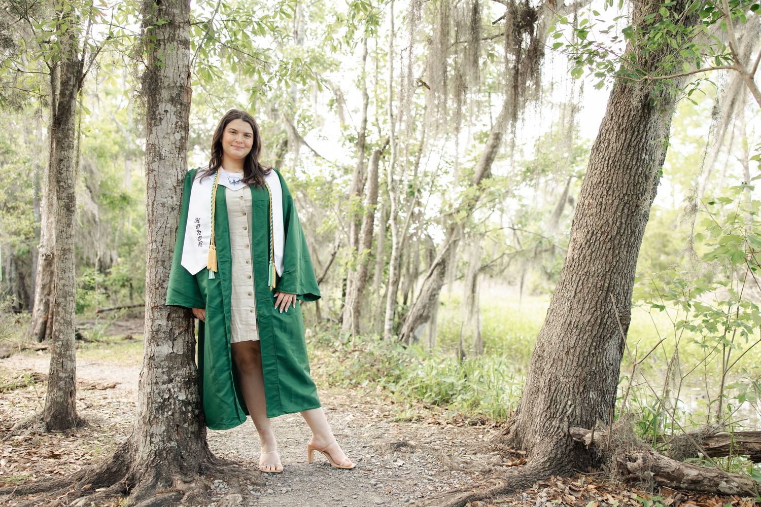 Person in a green blazer walks through a wooded area with sunlight filtering through the trees.