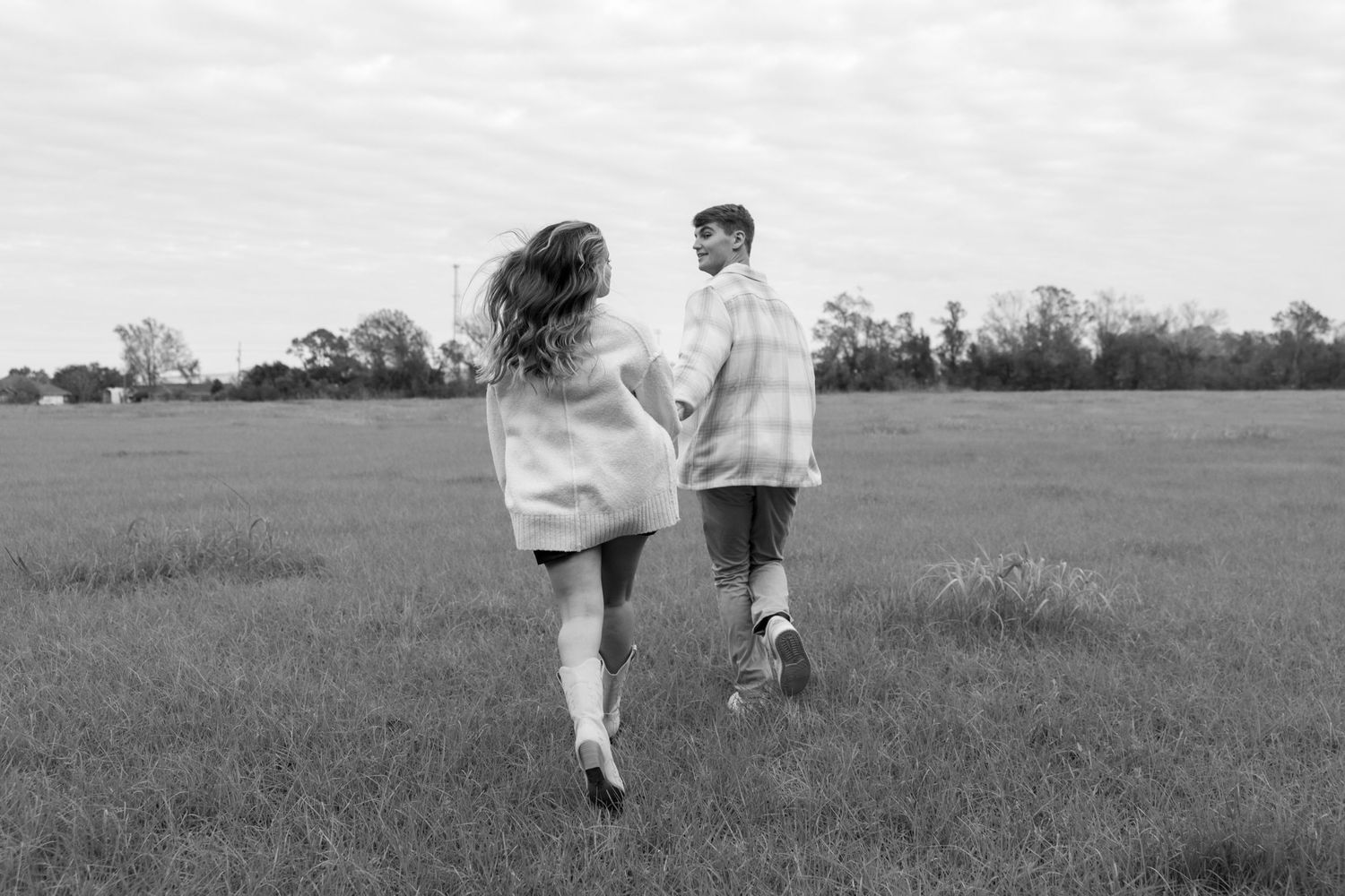 Two people running together in a grassy field captured in monochrome.