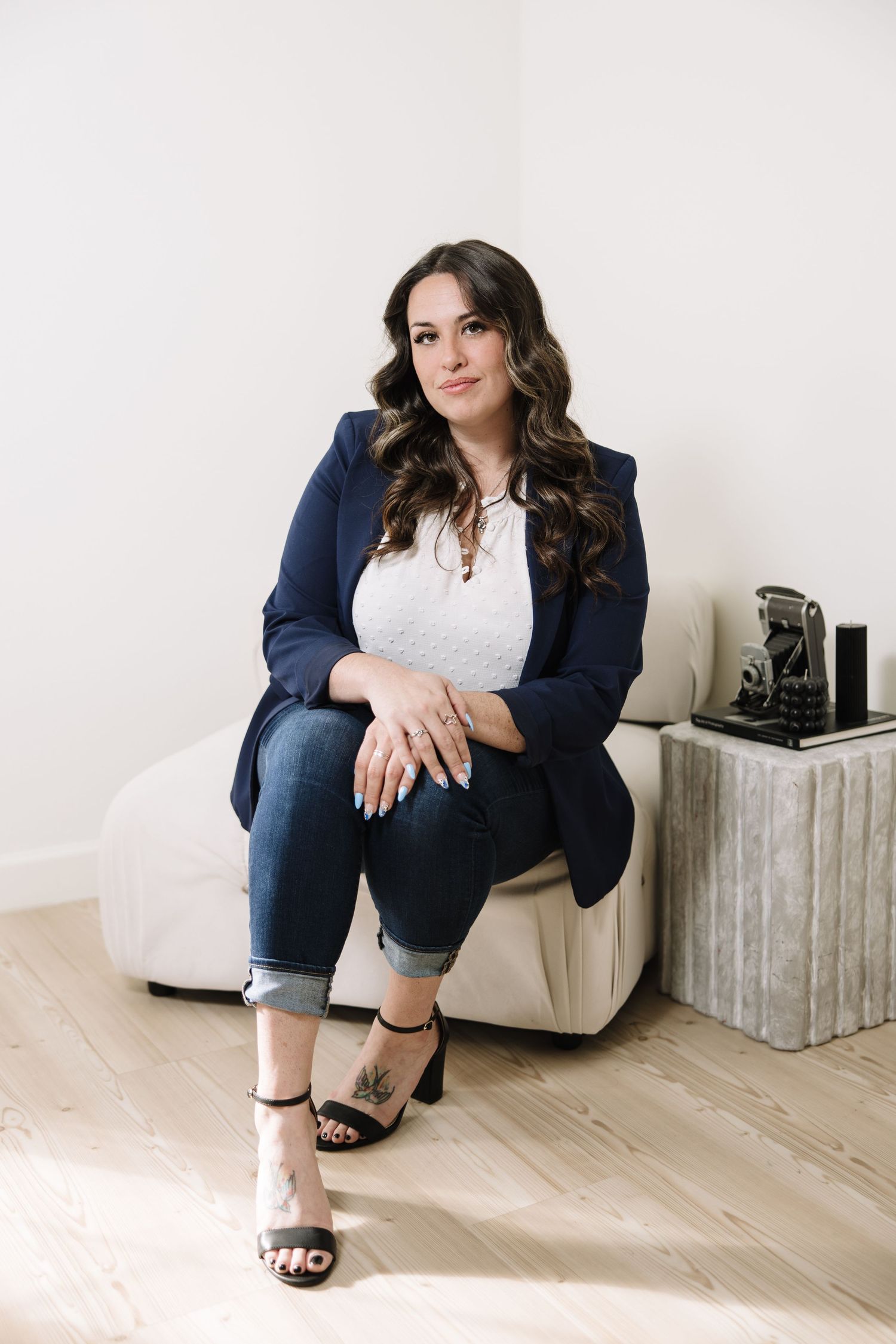 Professional woman in navy blazer and white top poses against light background in five different seated positions.
