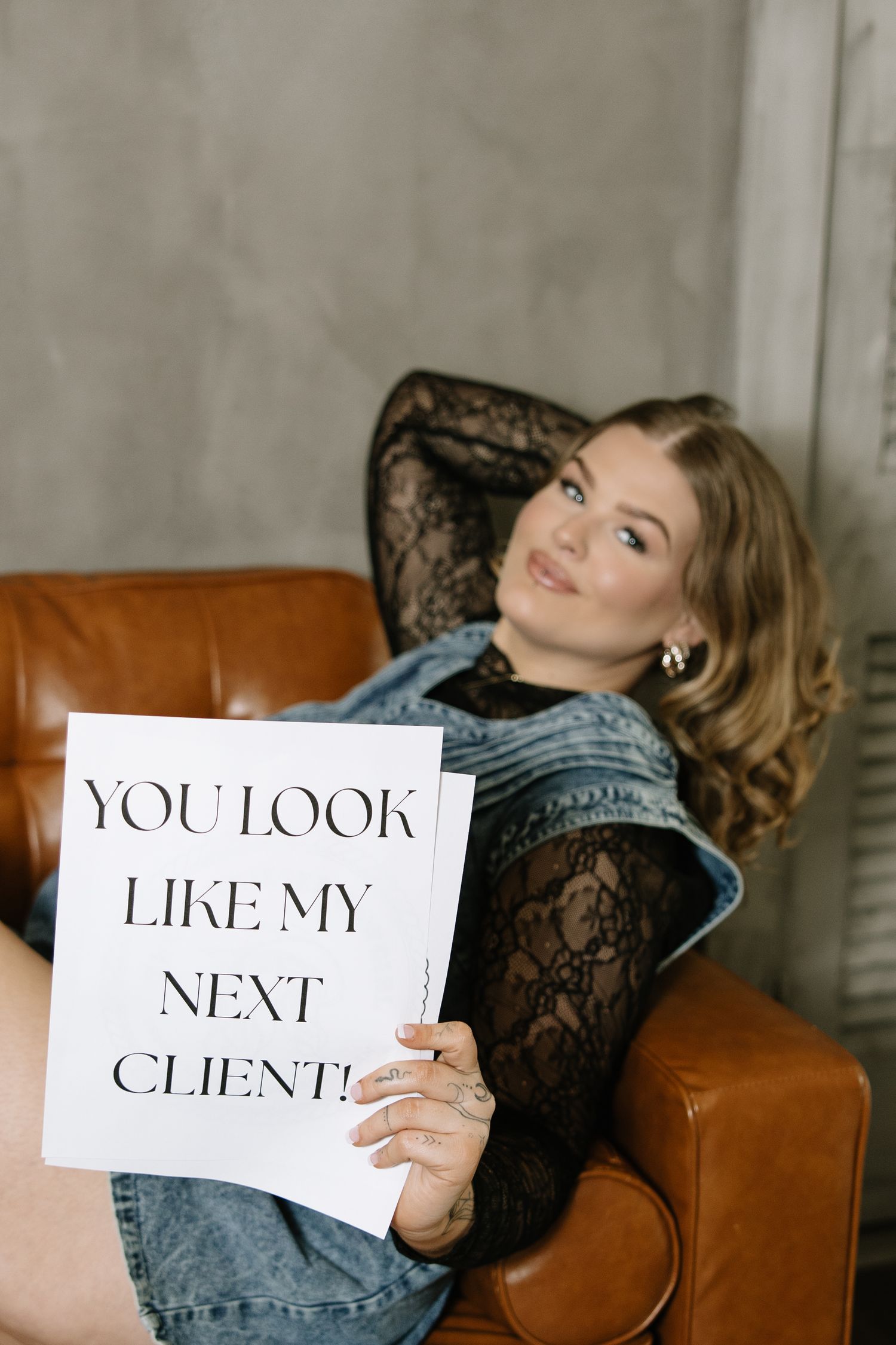 Artistic boudoir photography featuring text cards and lace details on a brown leather couch.