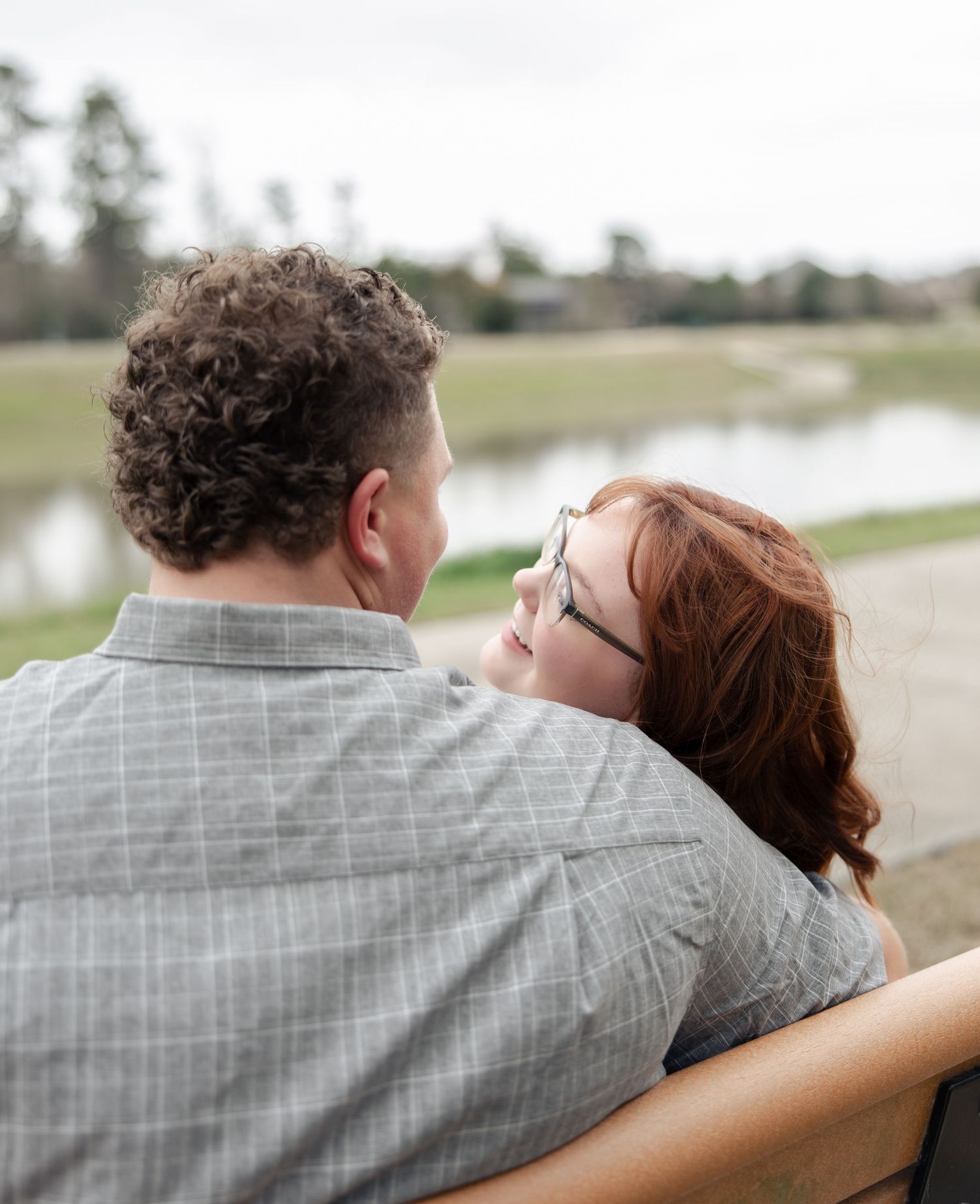 A couple shares an intimate moment while sitting on a bench near a lake.