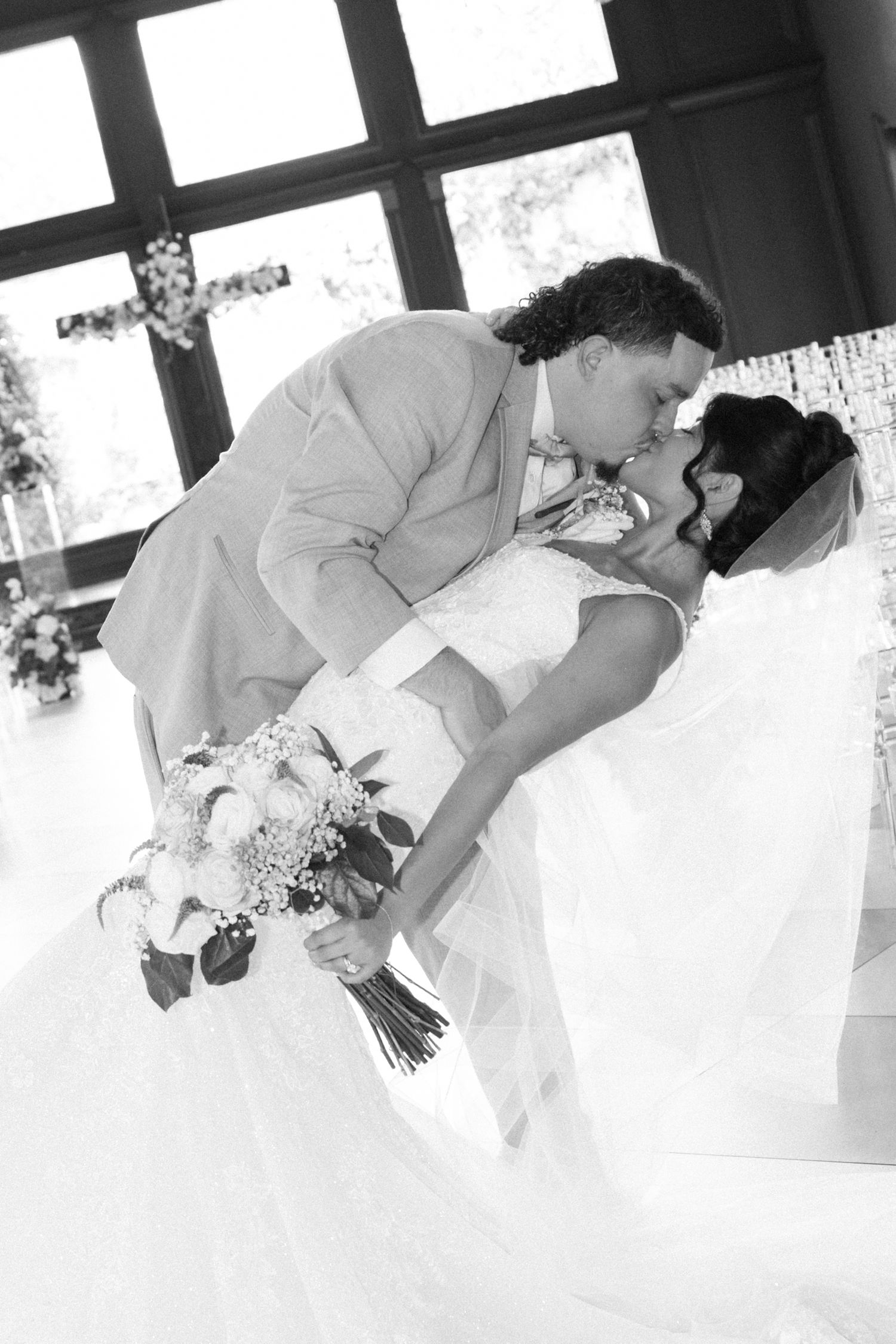 Romantic black and white wedding photo of a couple sharing a dip kiss.