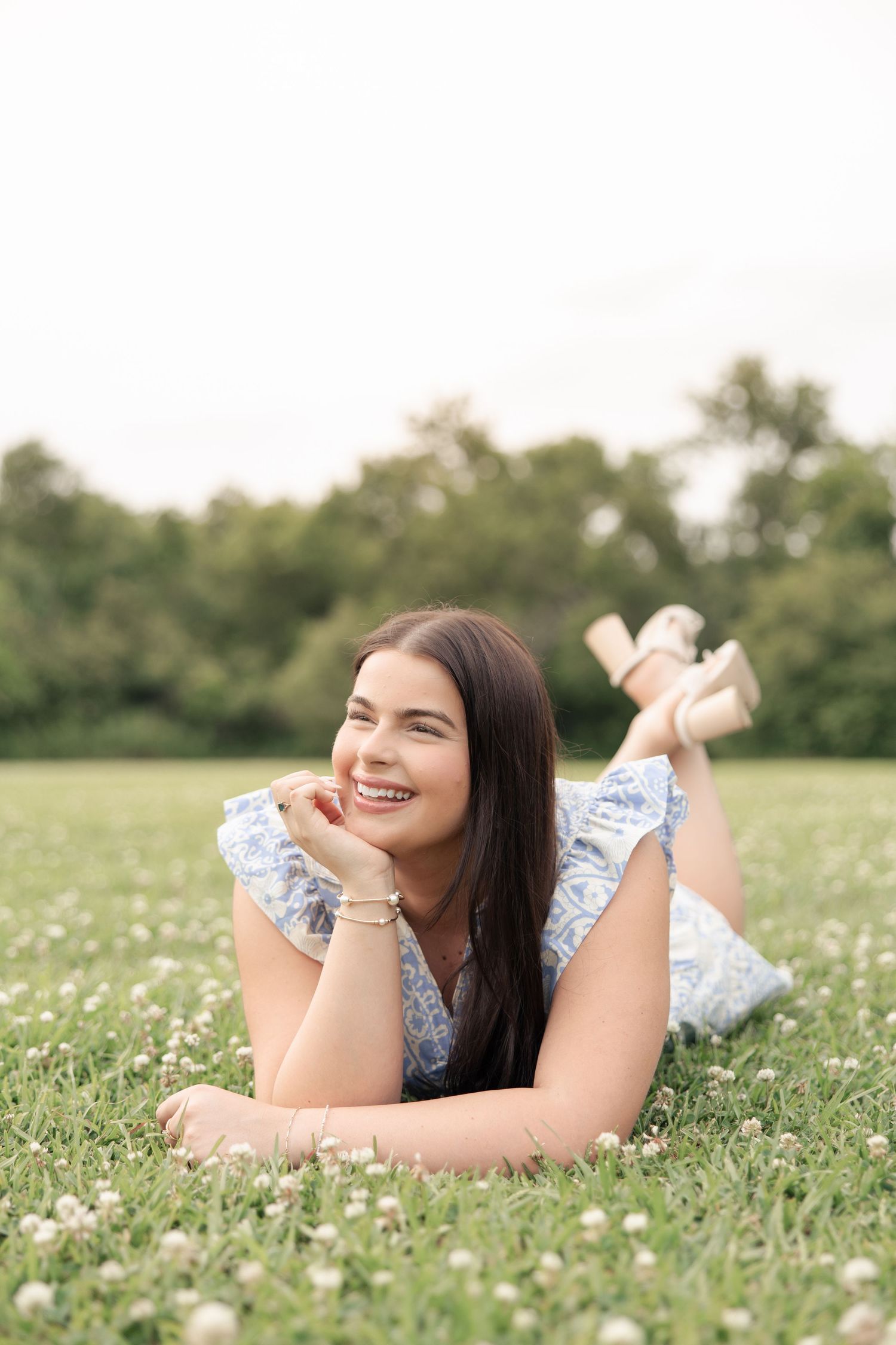 Person in blue floral dress lying in field of white flowers.