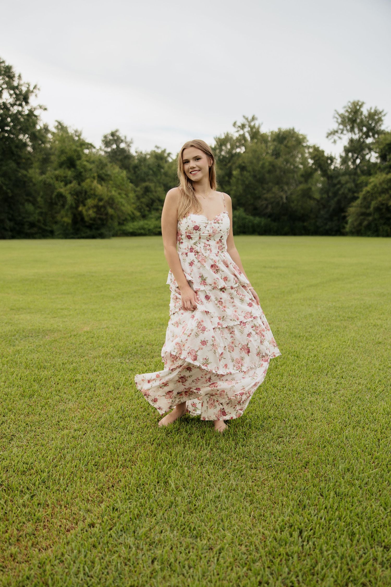 A floral dress flows in the breeze against a green grass backdrop.