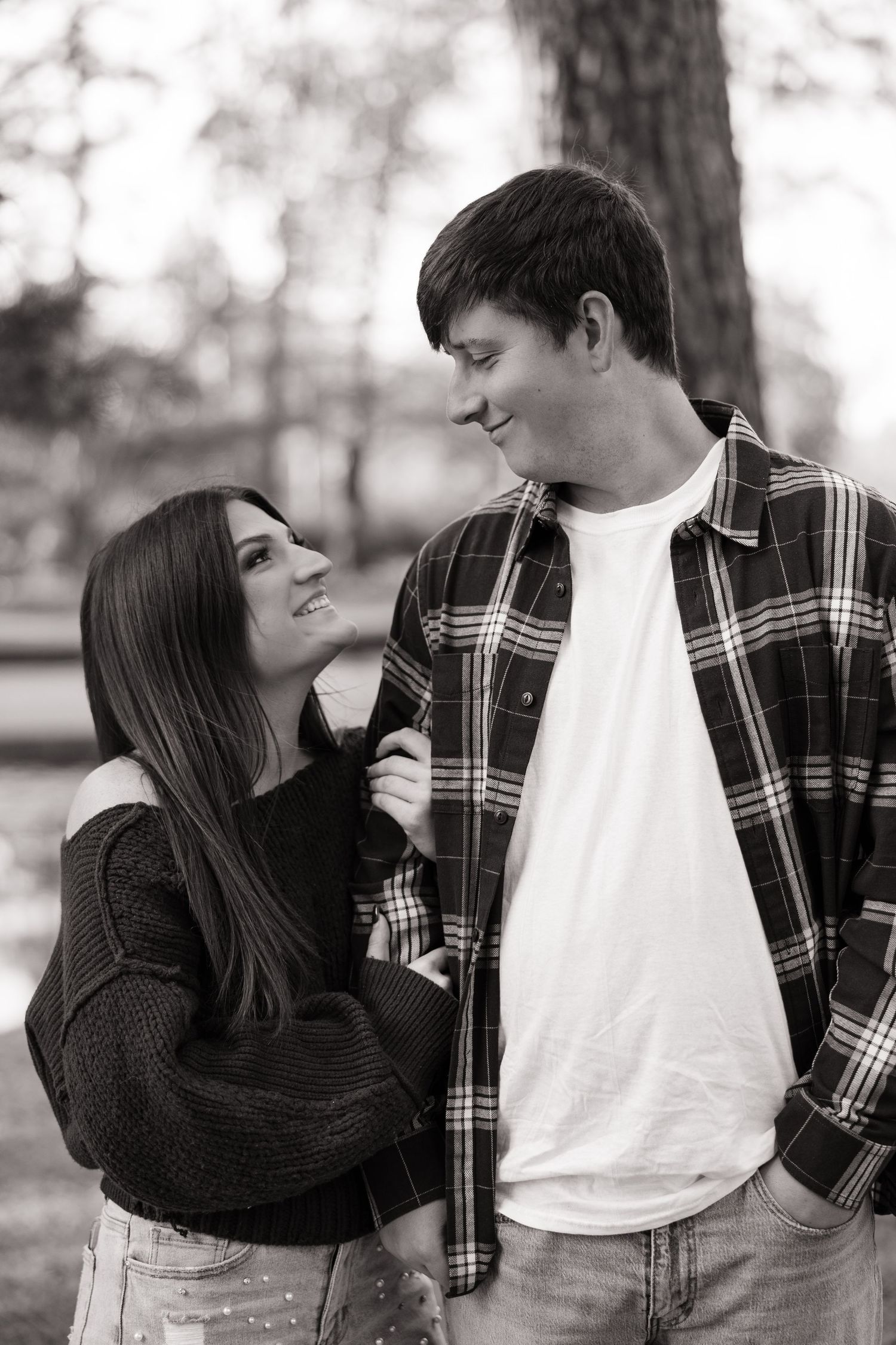 Black and white photo series showing a couple in a plaid shirt and black sweater sharing playful moments outdoors.