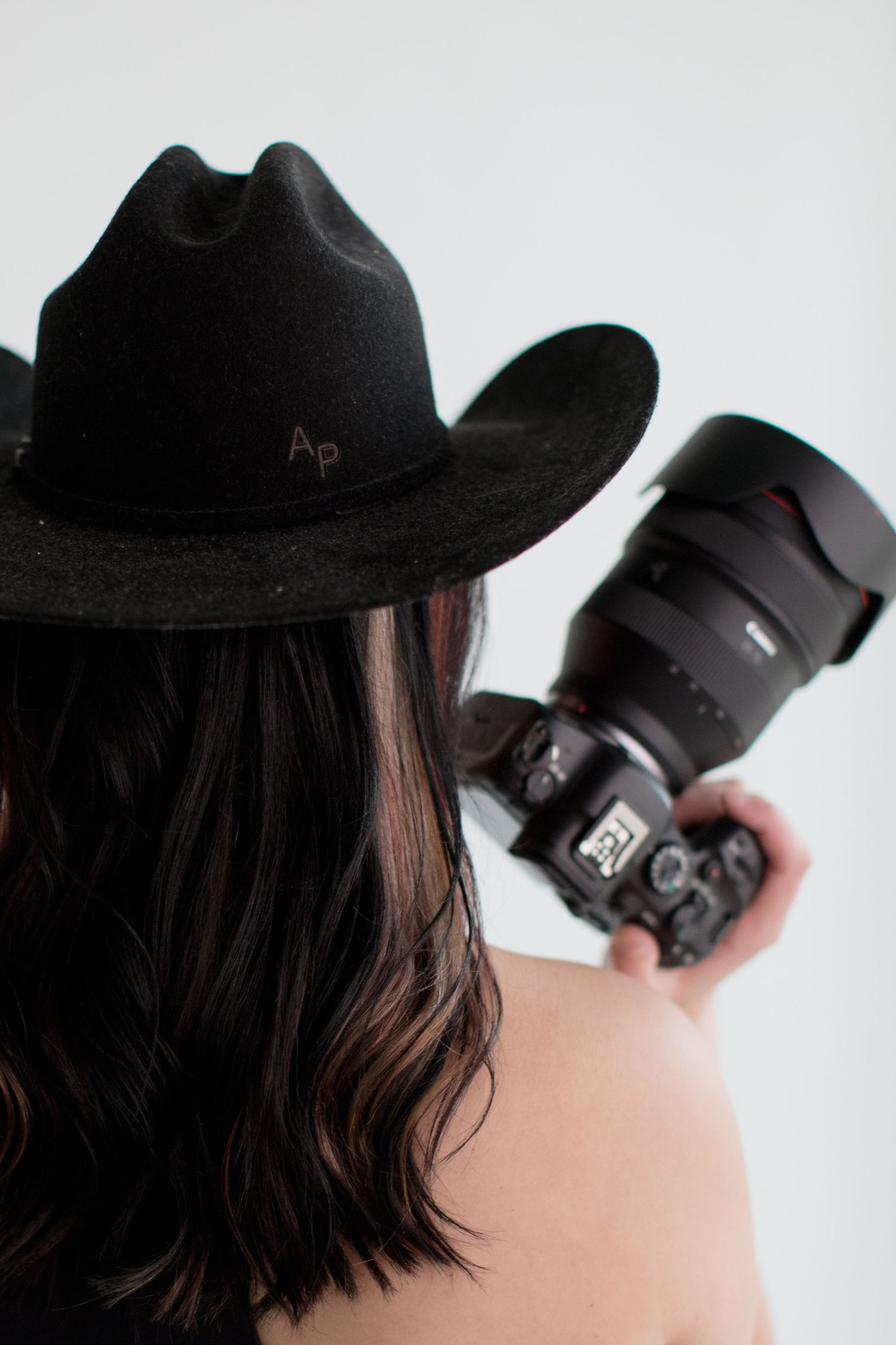Creative self-portrait series with camera equipment and black cap.