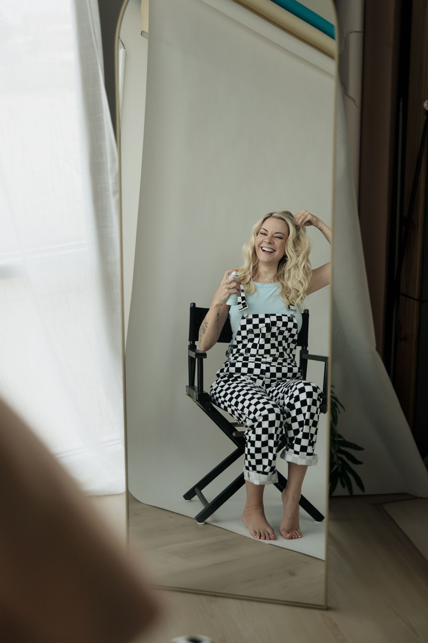 Mirror reflection of someone sitting in director's chair wearing black and white checkered outfit.