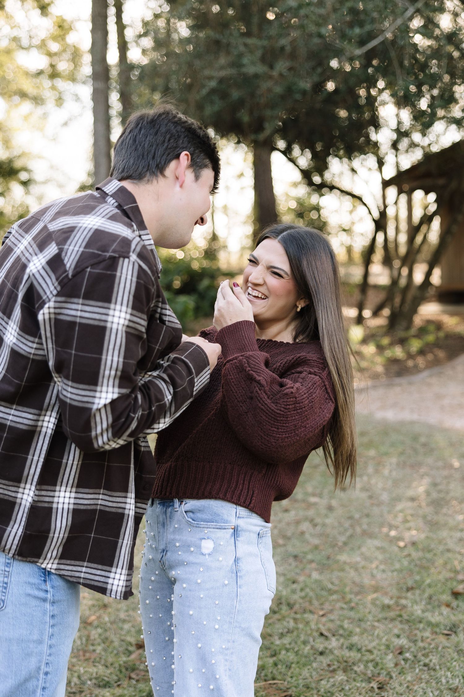 Candid photo sequence of a couple in casual fall outfits laughing and playing in a wooded setting.