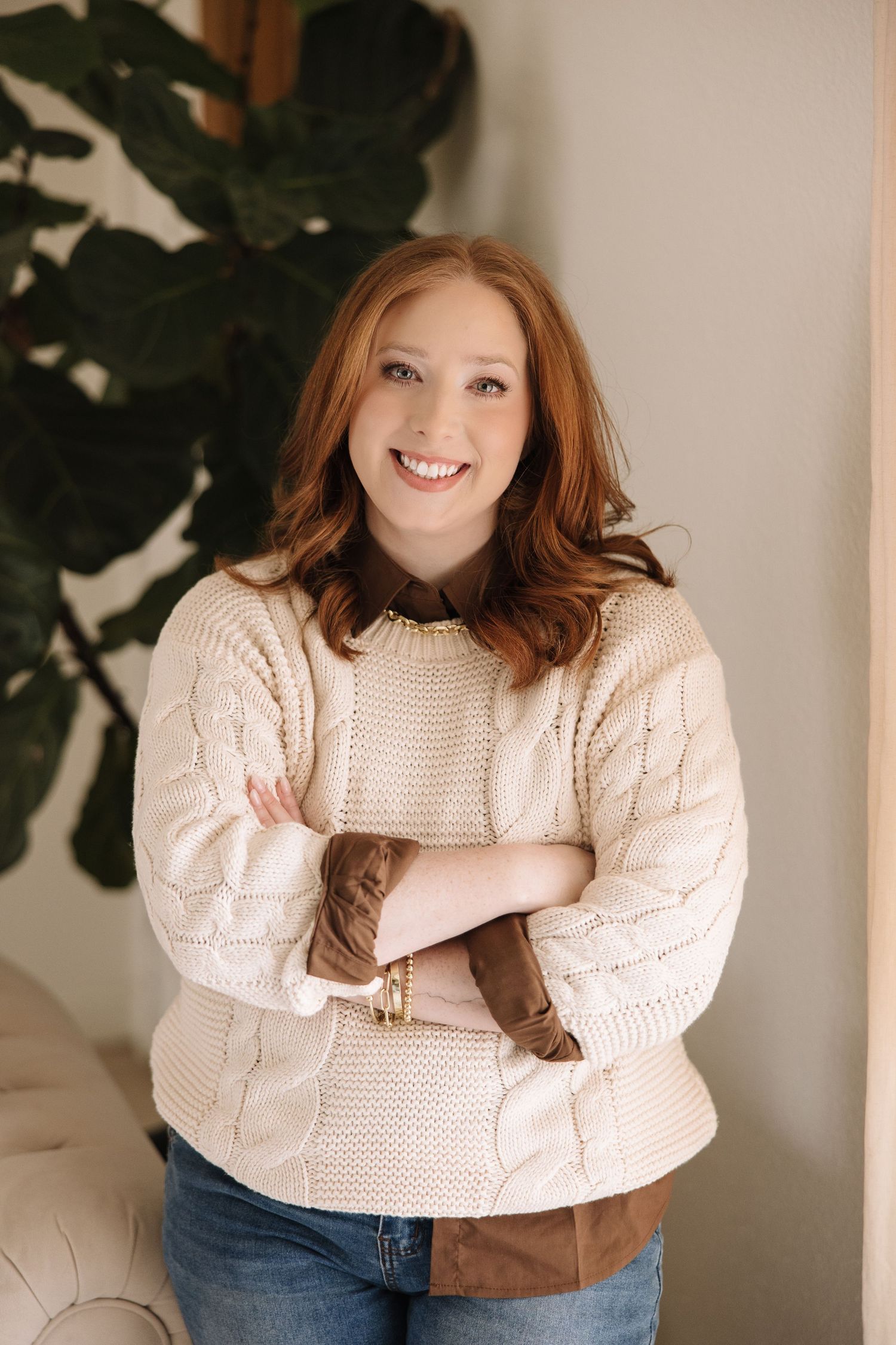 Cozy winter fashion shots featuring a cream cable knit sweater and indoor greenery.