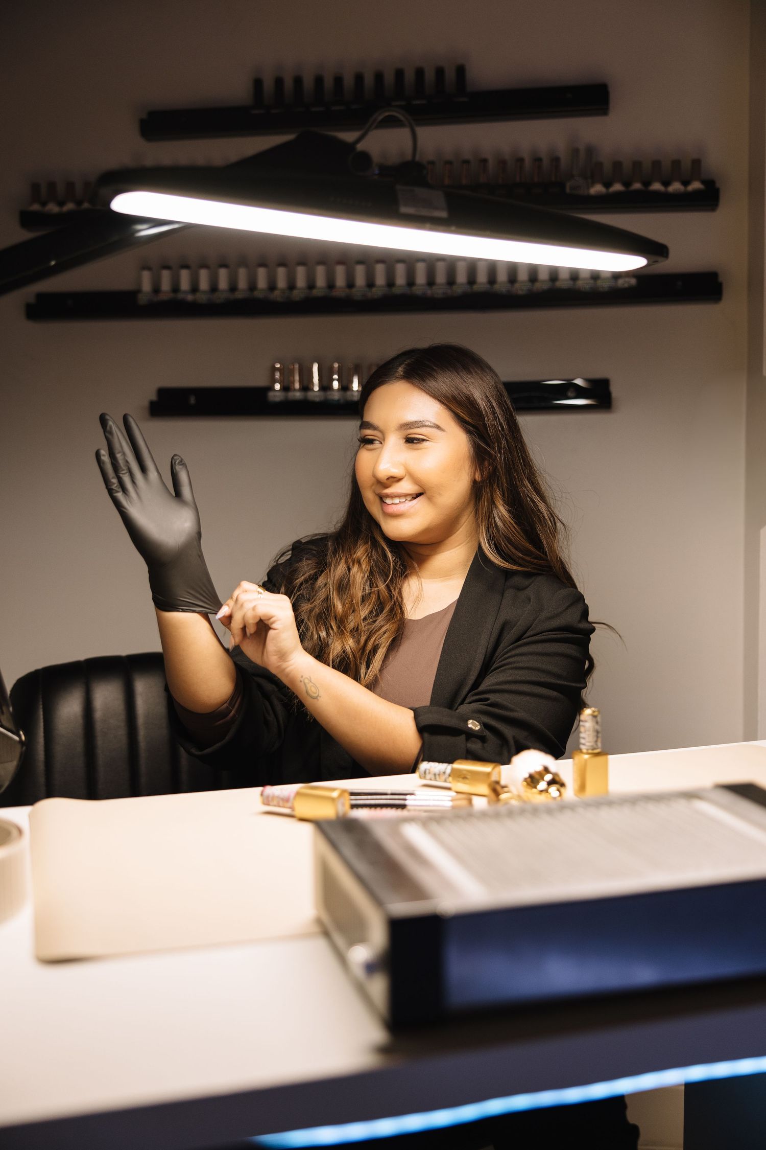 A person sits at a desk in a dimly lit office space with overhead lighting and black chairs.